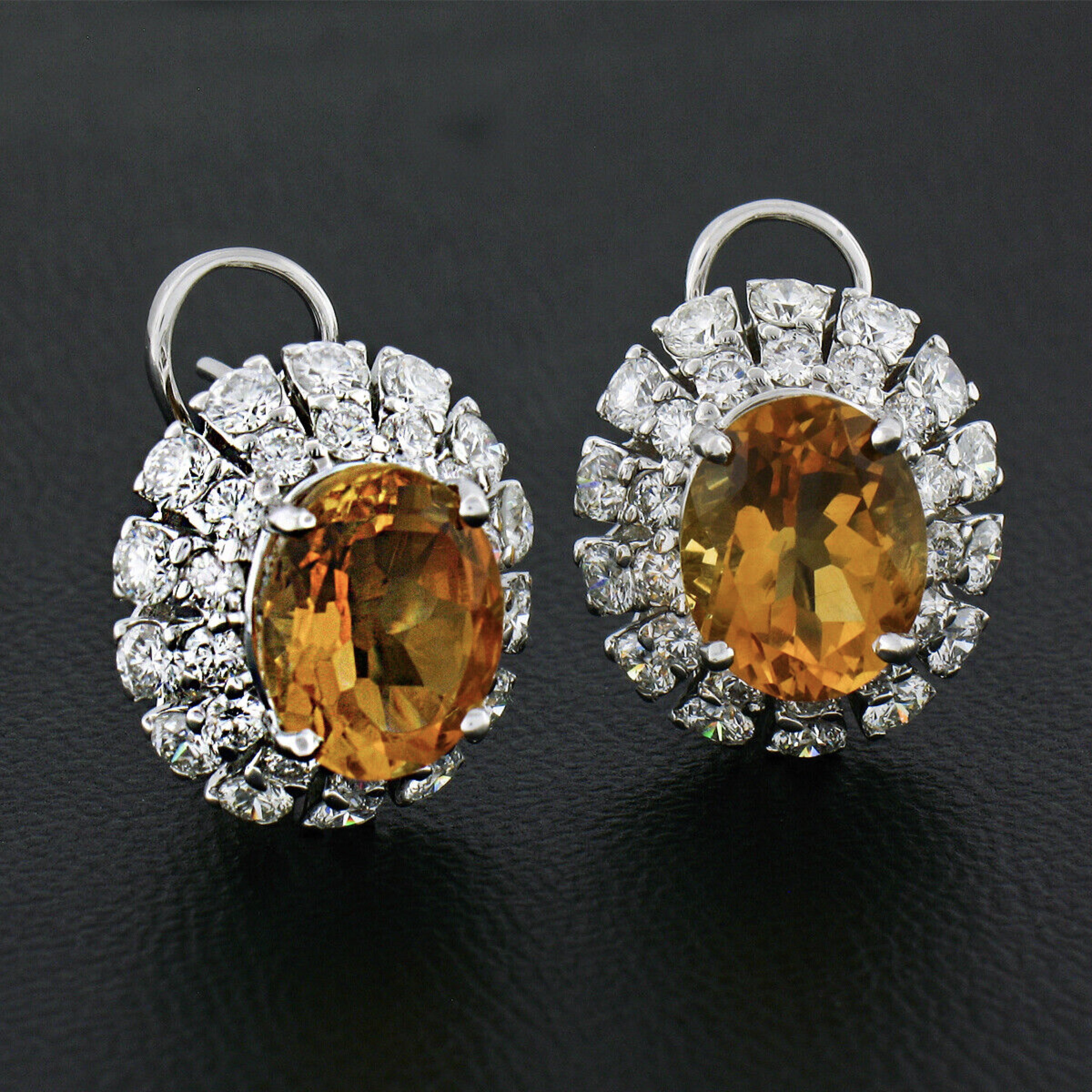 Cette paire de boucles d'oreilles en citrine et diamant est très bien réalisée en or blanc massif 18 carats et présente des citrines ovales taillées en brillant, entourées d'un double halo de diamants. La citrine présente une couleur jaune orangé