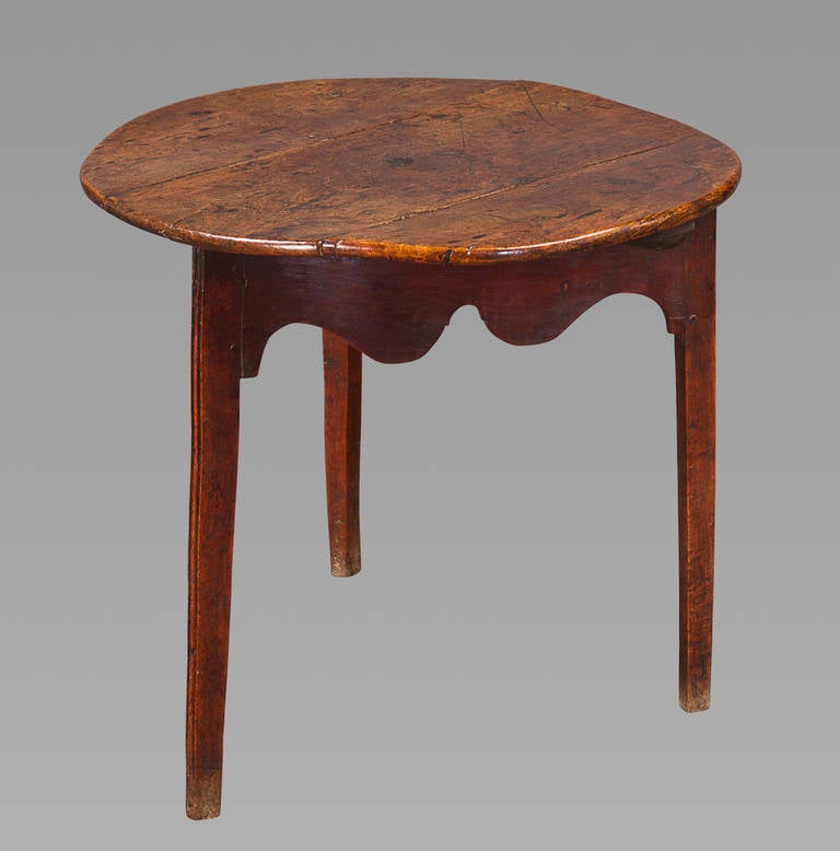 An excellent three-legged elm-top cricket table with shaped skirt, retaining a good dry surface to the feet. The pegged three-plank top has developed a very pleasant warp that adds much character to the piece.