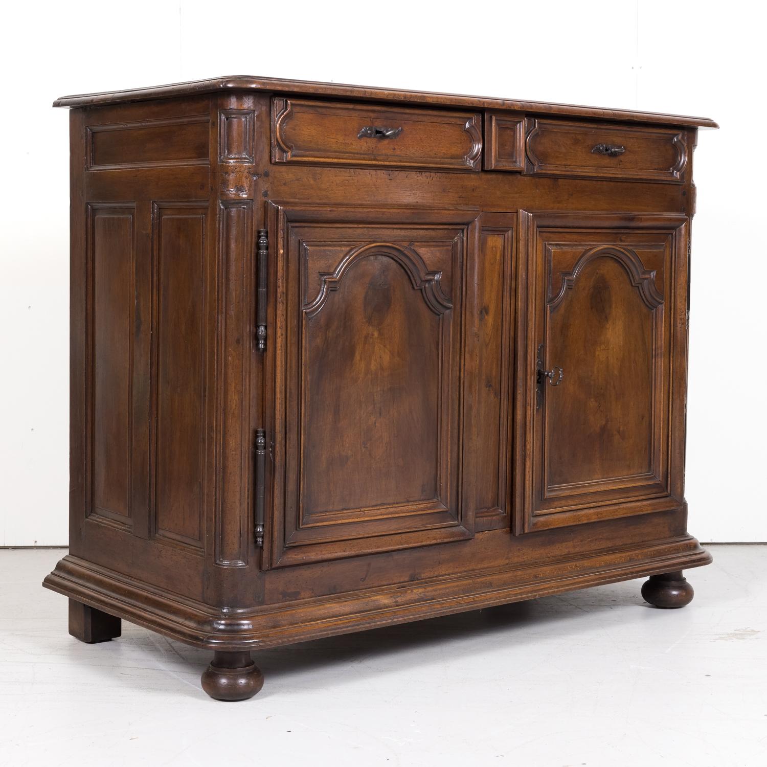 A beautiful 18th century French period Louis XIV buffet handcrafted by talented artisans in Lyon of solid walnut, circa 1700. Having a beveled, rounded edge plank top above two large raised, molded panel drawers with a secret center drawer over two