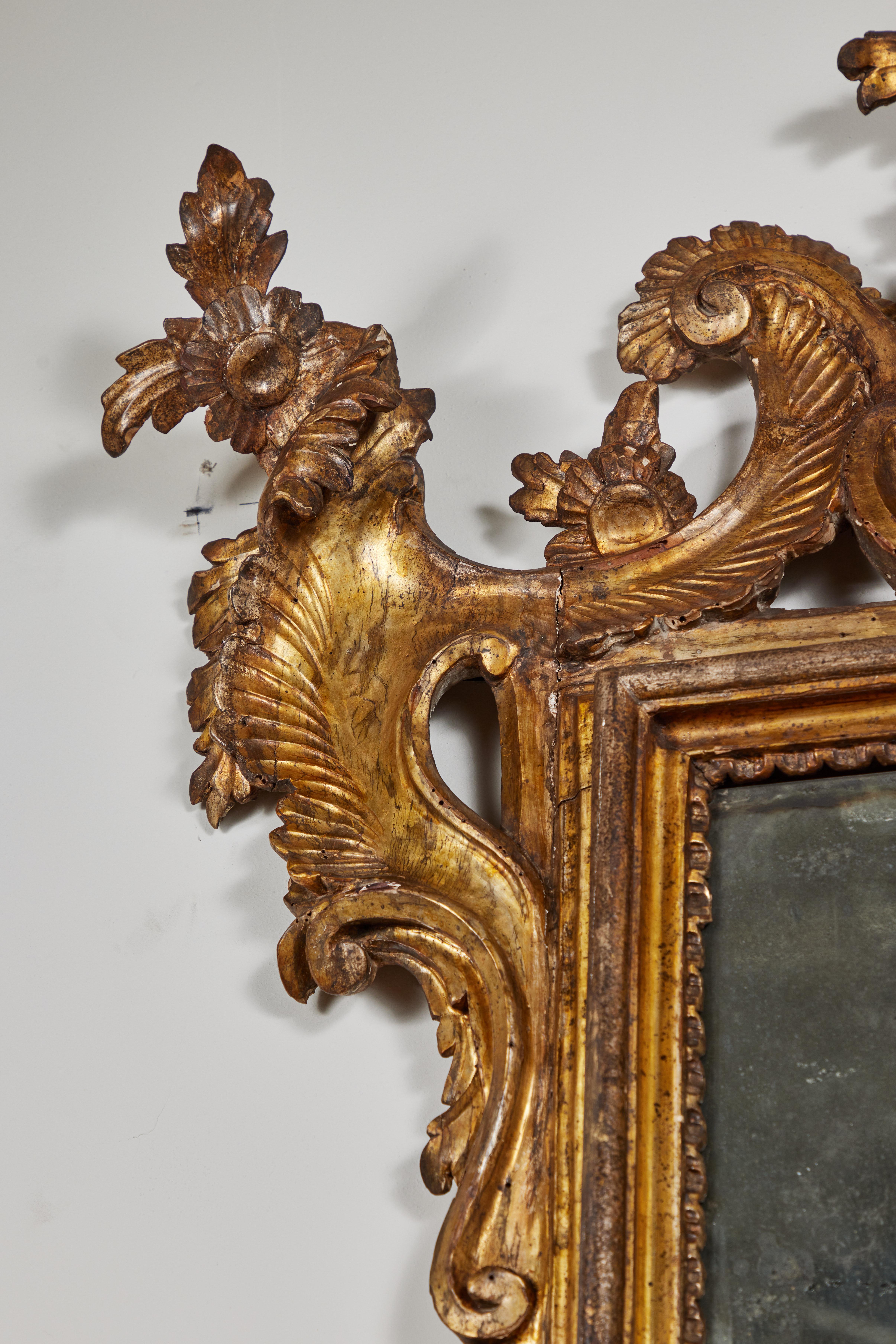 Beautifully hand-carved, gessoed and 22k gold gilded, c. 1760 pier mirror inset with its original two panels of mercury glass. The whole embellished with relief carved scrolls, and surmounted by a stunning crown with mercury glass medallion beneath