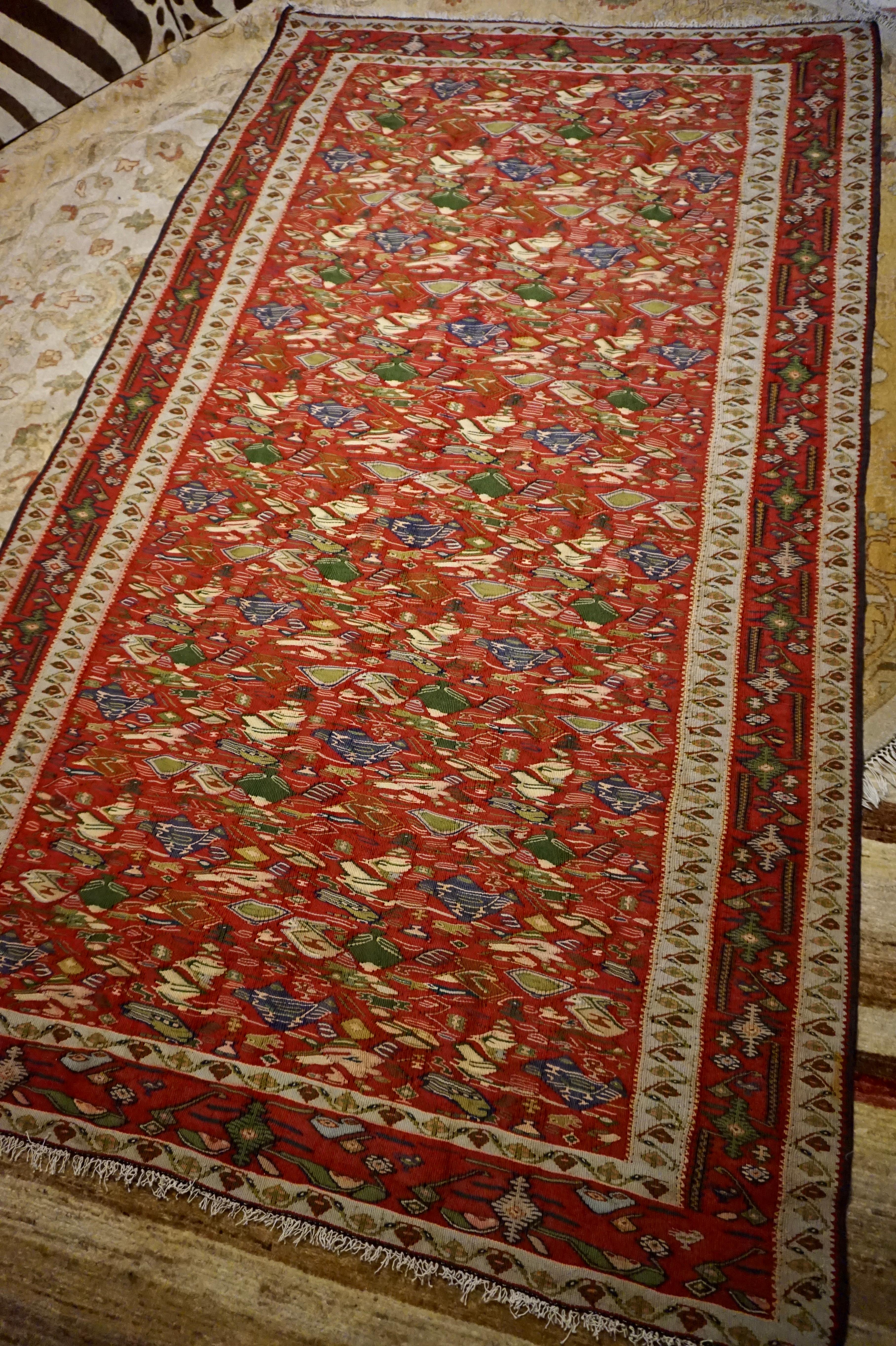 Rare and intricate bird patterns beautifully juxtaposed in a medley of vibrant hues, this kilim exudes refined weaving. An excellent size and unique subject matter makes it a must have statement piece that will not disappoint. Excellent condition