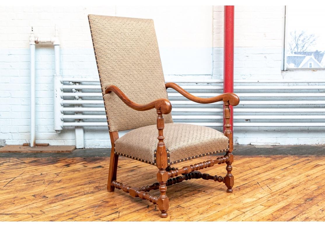 A very well made, sturdy and quite comfortable antique armchair with custom fabric treatment. The walnut hall chair with sloping tall back. The curved arms with scrolled ends and turned supports. Raised on elaborate turned front legs with bun feet