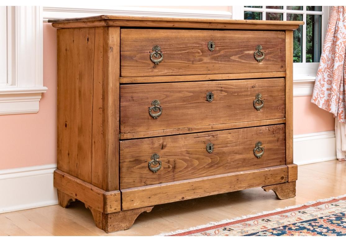 A three drawer chest in French Country style with large capacity dove-tail constructed drawers and charming Cottage form. The original pulls and drawer escutcheons have been replaced with intricate hanging  pulls  with fine form. Professionally