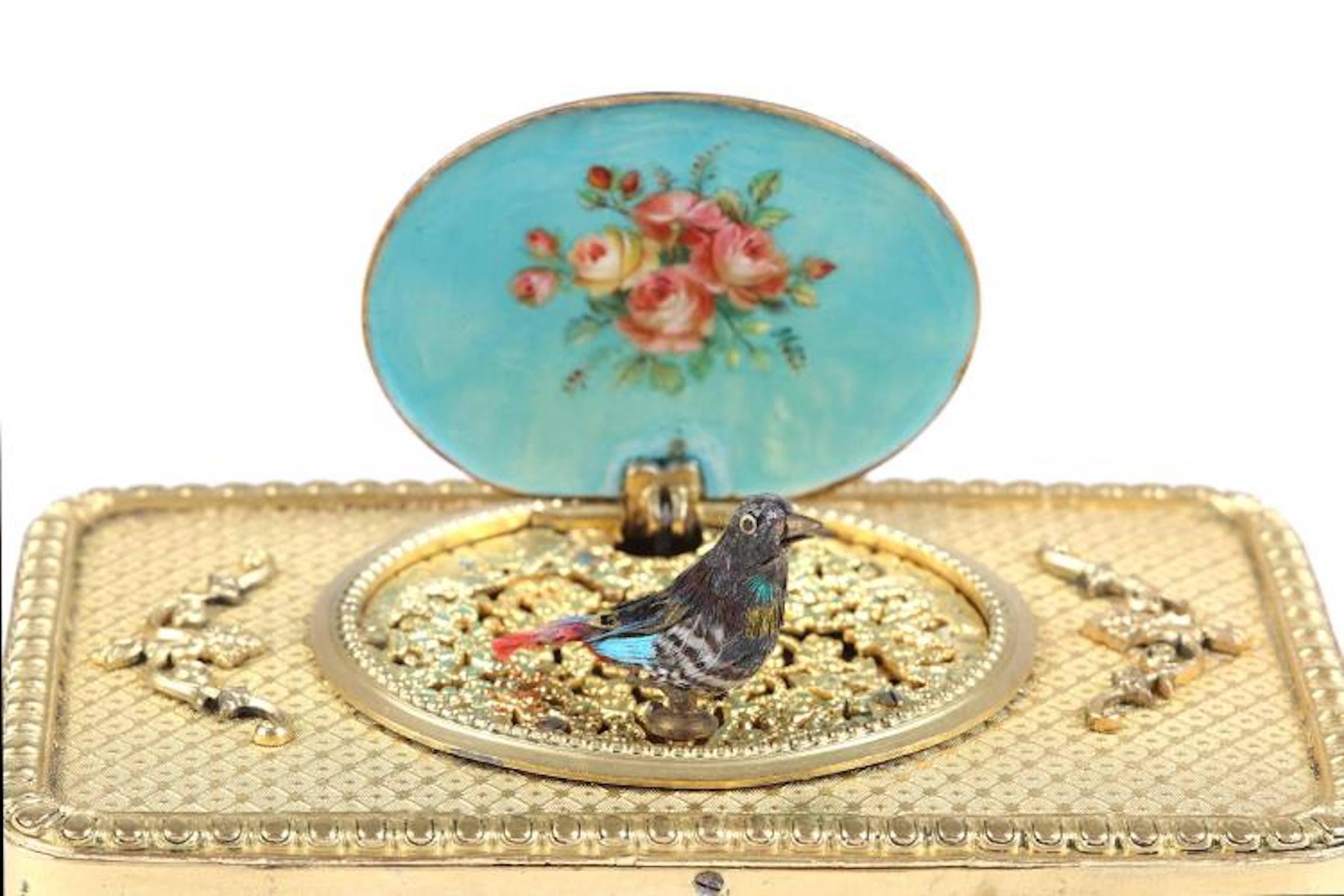 A fine 19th century Swiss marked .625 gold and enamel singing bird box 'Oiseaux Chantants' the rectangular box decorated with a continuous frieze of frolicking putti to the sides with an egg and dart border to the top and trellis pattern within,