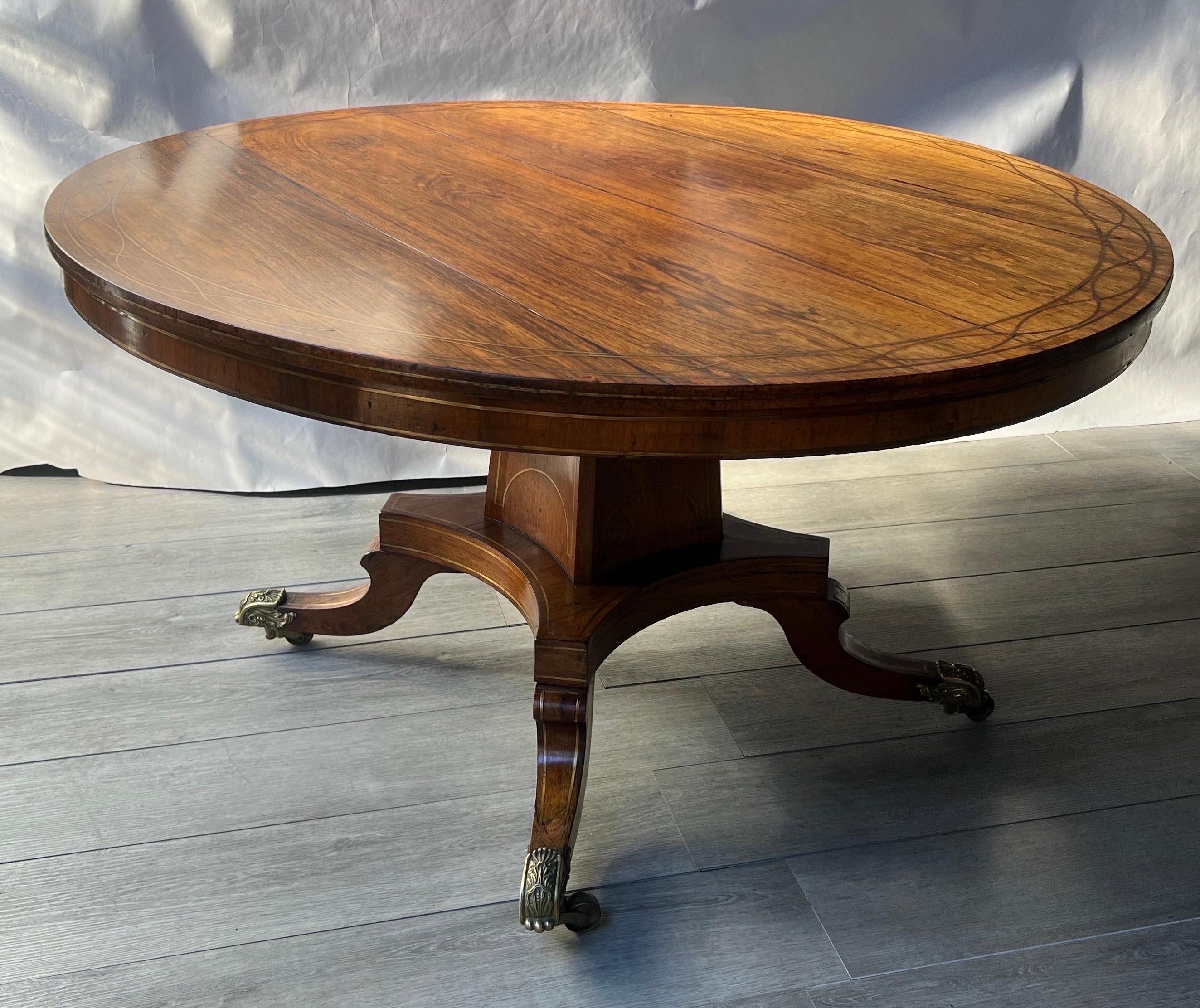 Fine 19th century brass inlaid rosewood English Regency period center table with original bronze feet on castors. Great size and scale- could easily be used as a dining or breakfast table as well 