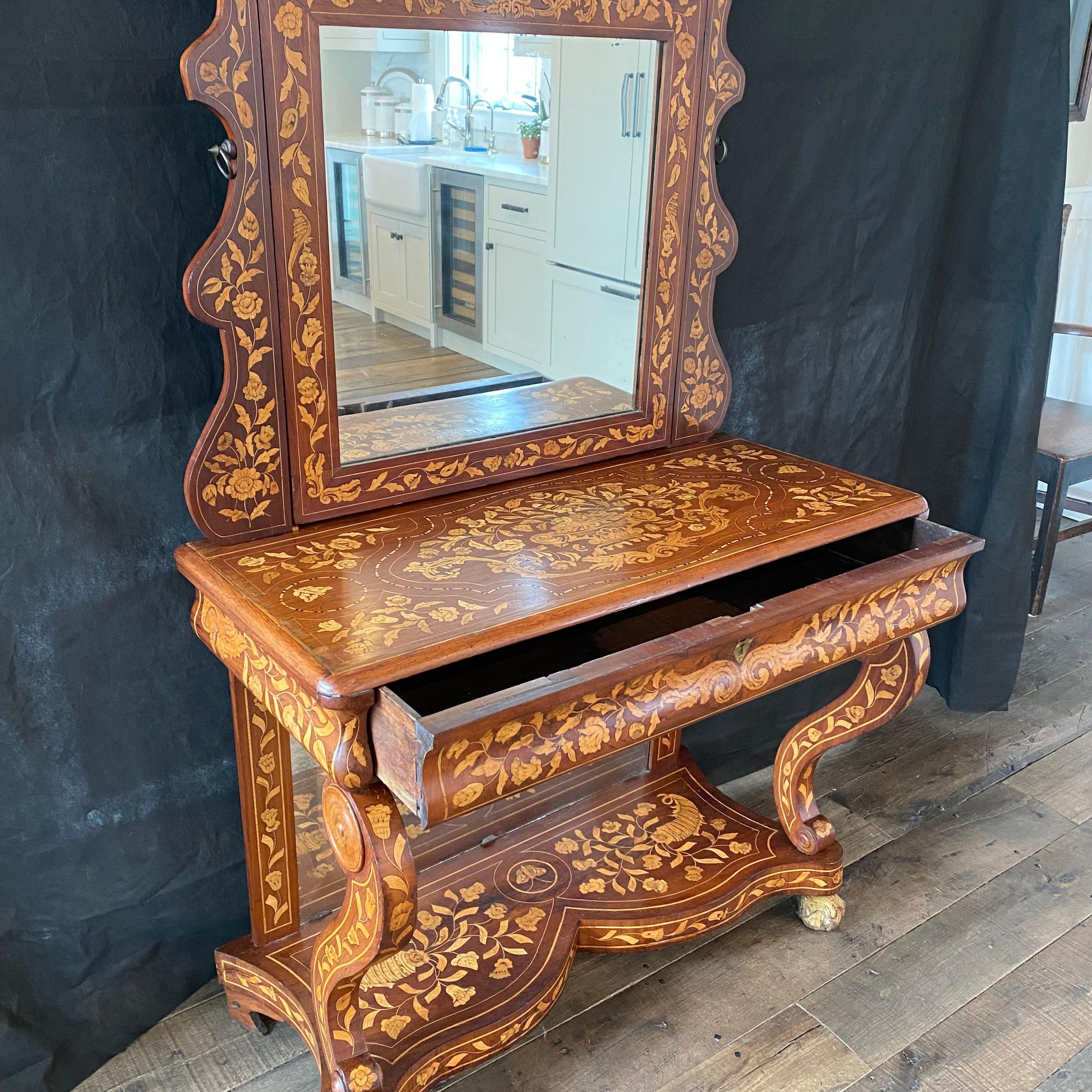 Dutch mahogany and marquetry inlaid dressing table, the mirror between carved and shaped tapered uprights to the base section fitted with long frieze drawer over a back mirror on the base. Back, mirror frame, dressing table top, sides, base and legs