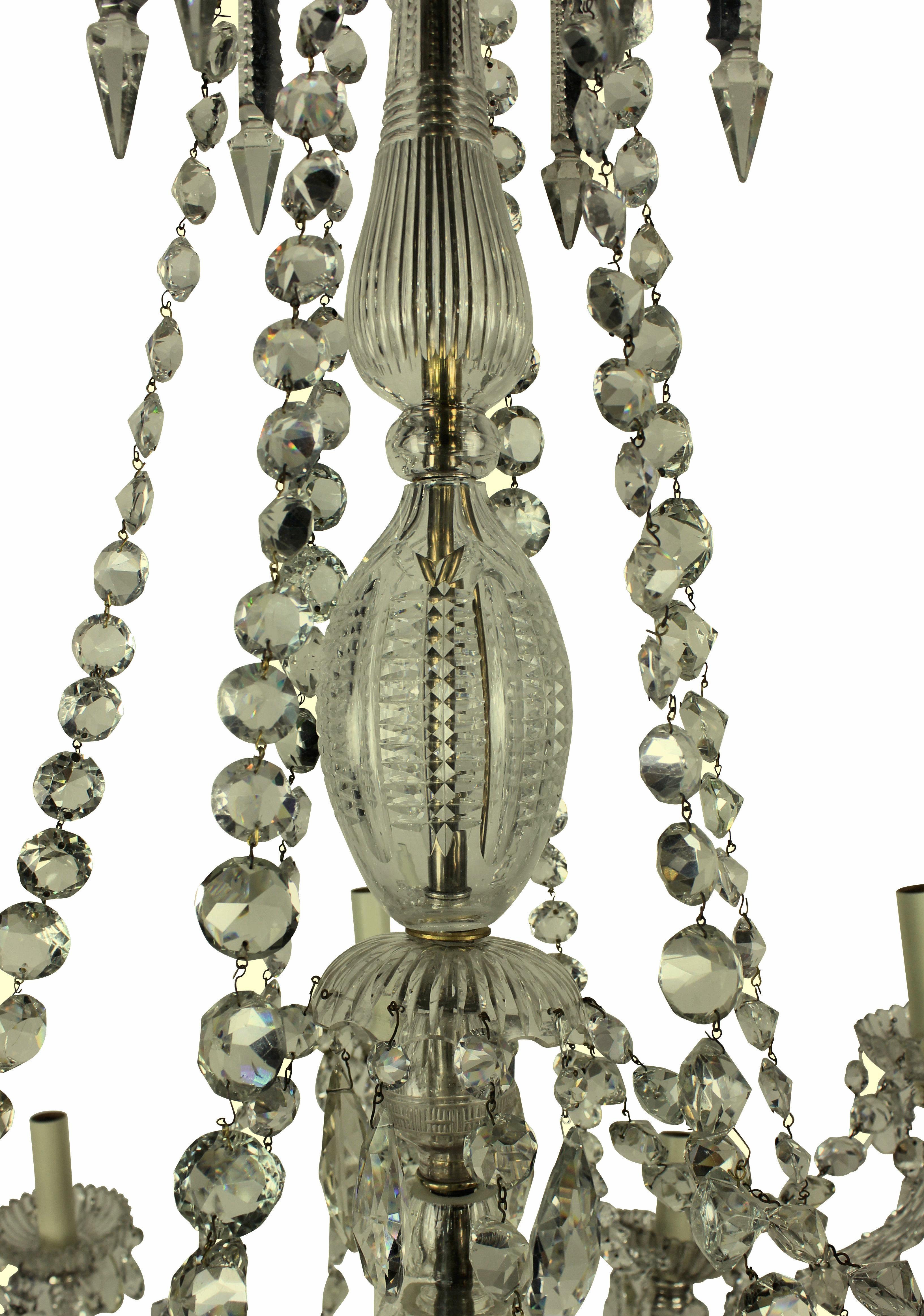 A fine English cut-glass chandelier of very fine quality by Perry & Co. of New Bond Street. Tiered with twelve faceted scrolled branches issuing stellar cut pans and nozzles from lobed wells and baluster vase shaped column, hung with faceted