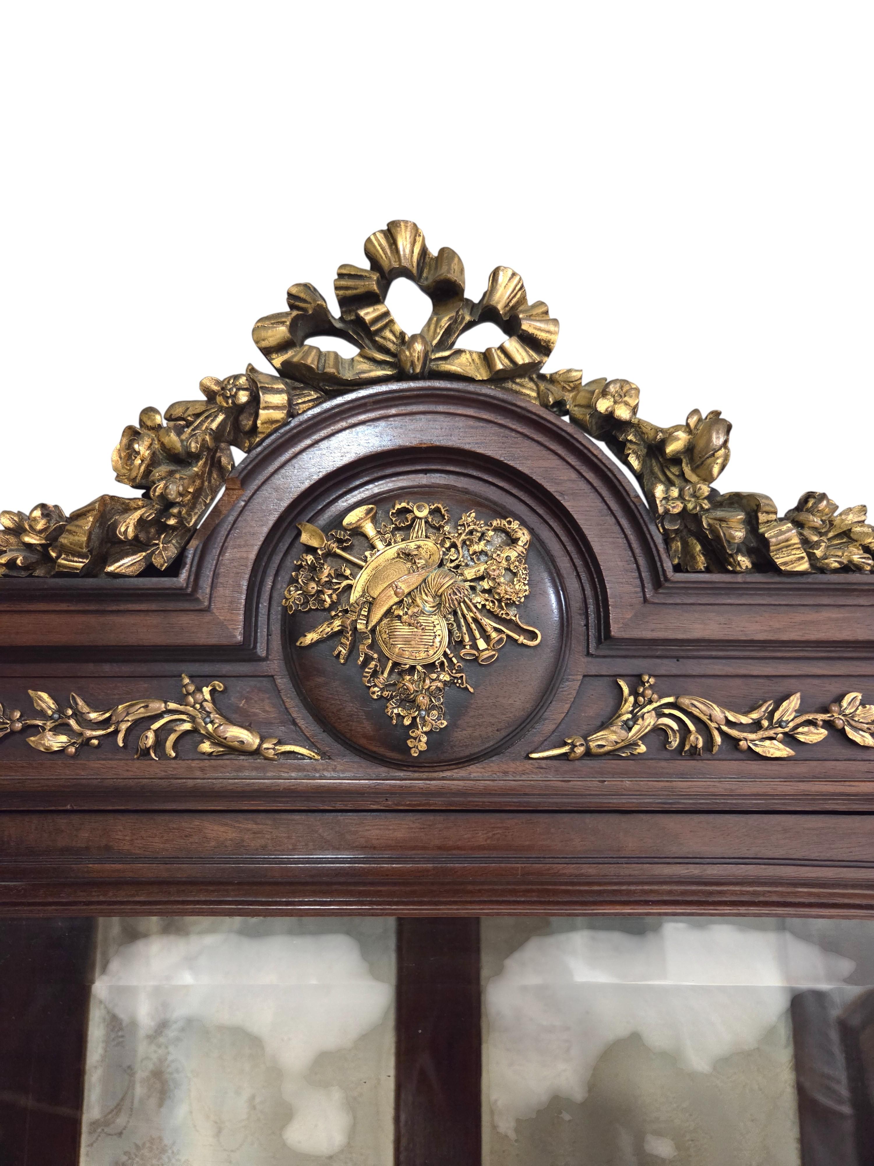 Raffinata vetrinetta francese in stile Luigi XVI della fine del XIX secolo, siglata H.D. e attribuita a Henry Dasson.
 La vetrina è caratterizzata da un design a tre sezioni con porte e pannelli laterali in vetro smussato, che consentono una piena