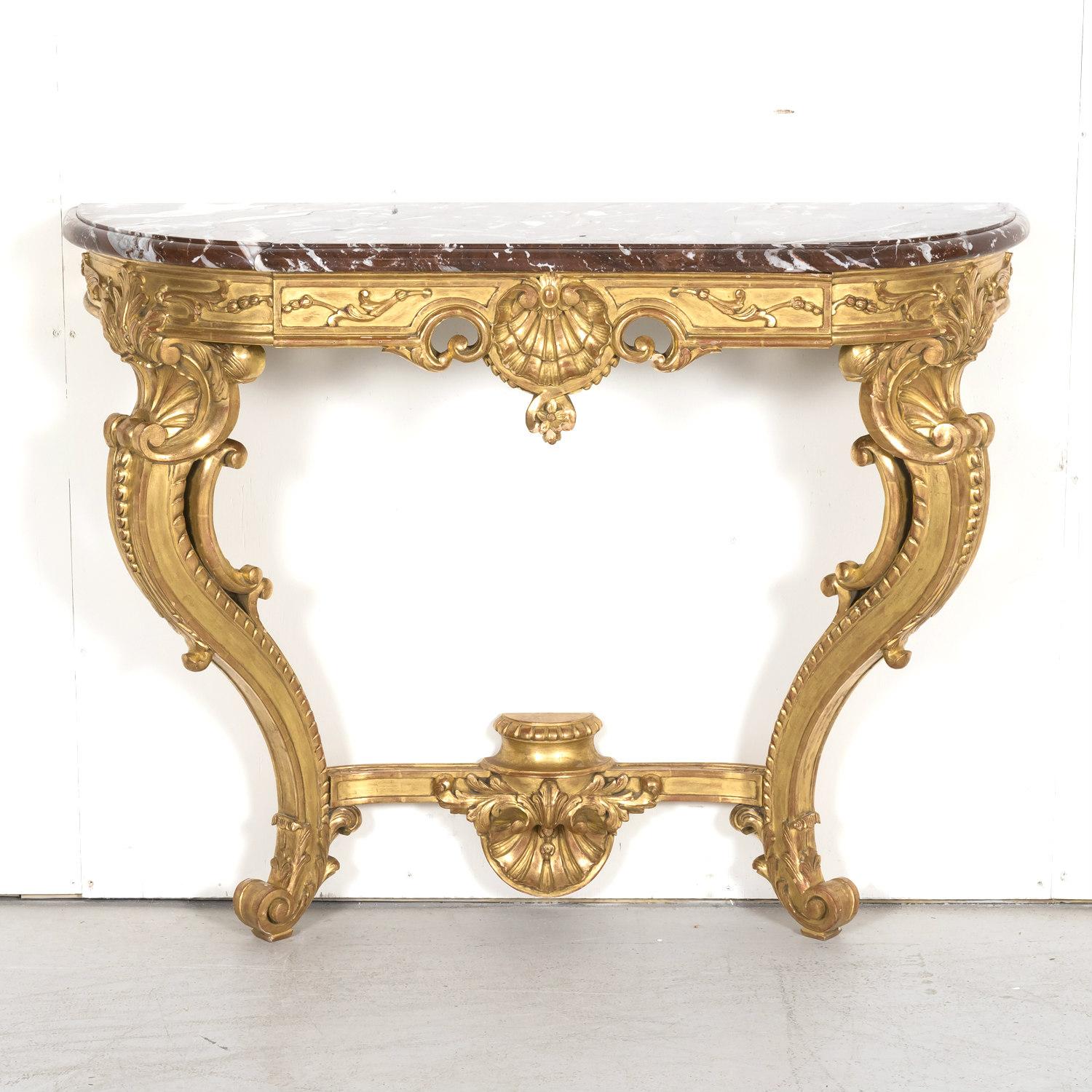 A fine 19th Century French Louis XV Rococo style giltwood wall mounted console having the original Rouge Royal marble top above a giltwood frame with rounded corners. Featuring an intricately carved frieze with a central shell and foliate motifs,