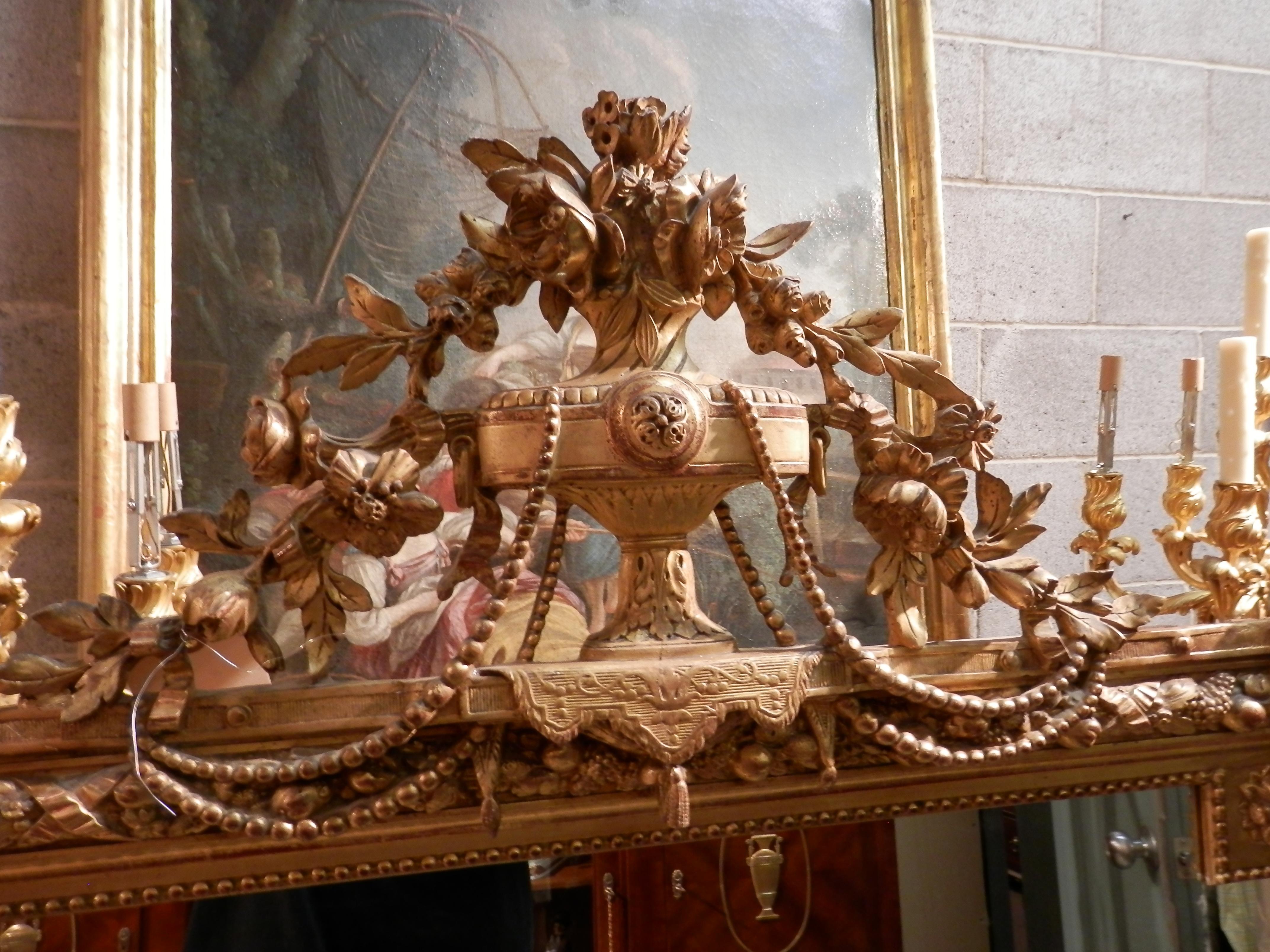 Beautifully carved and gilt 19th century French Louis XVI mirror. Urn with swags on the crest with carved floral details.