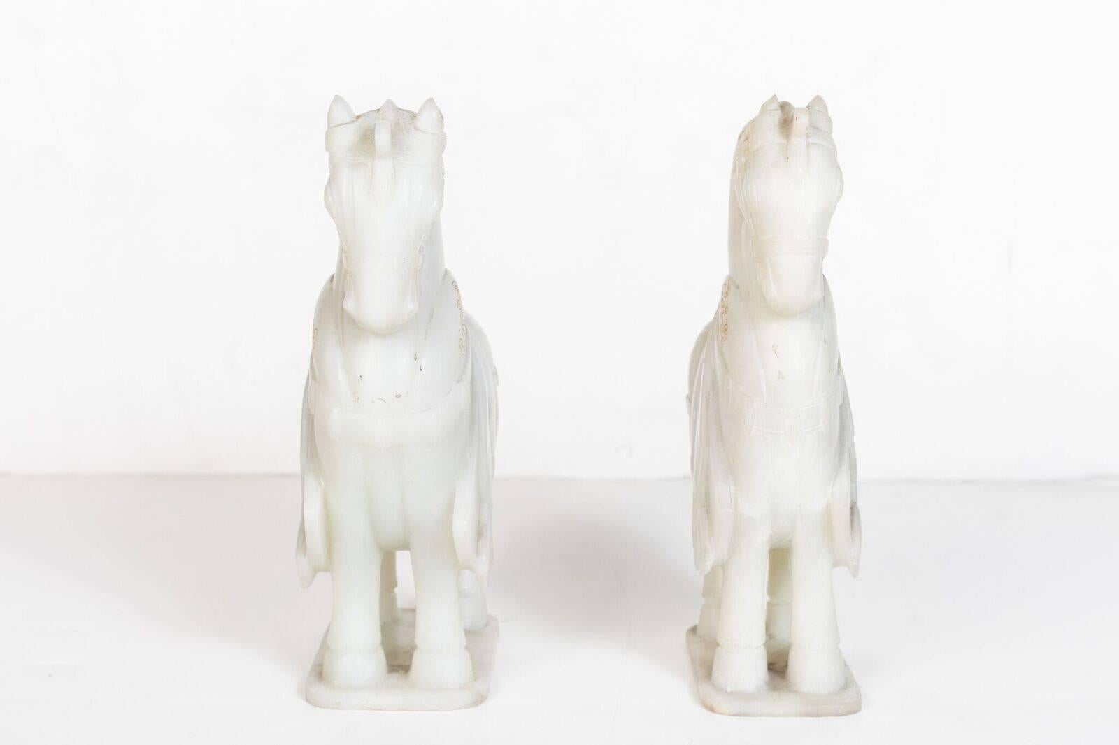 Pair of elegant, hand-carved, white hardstone, Chinese horses with gilded details. Each outfitted with saddles, bridles and featuring braided rolled tails.