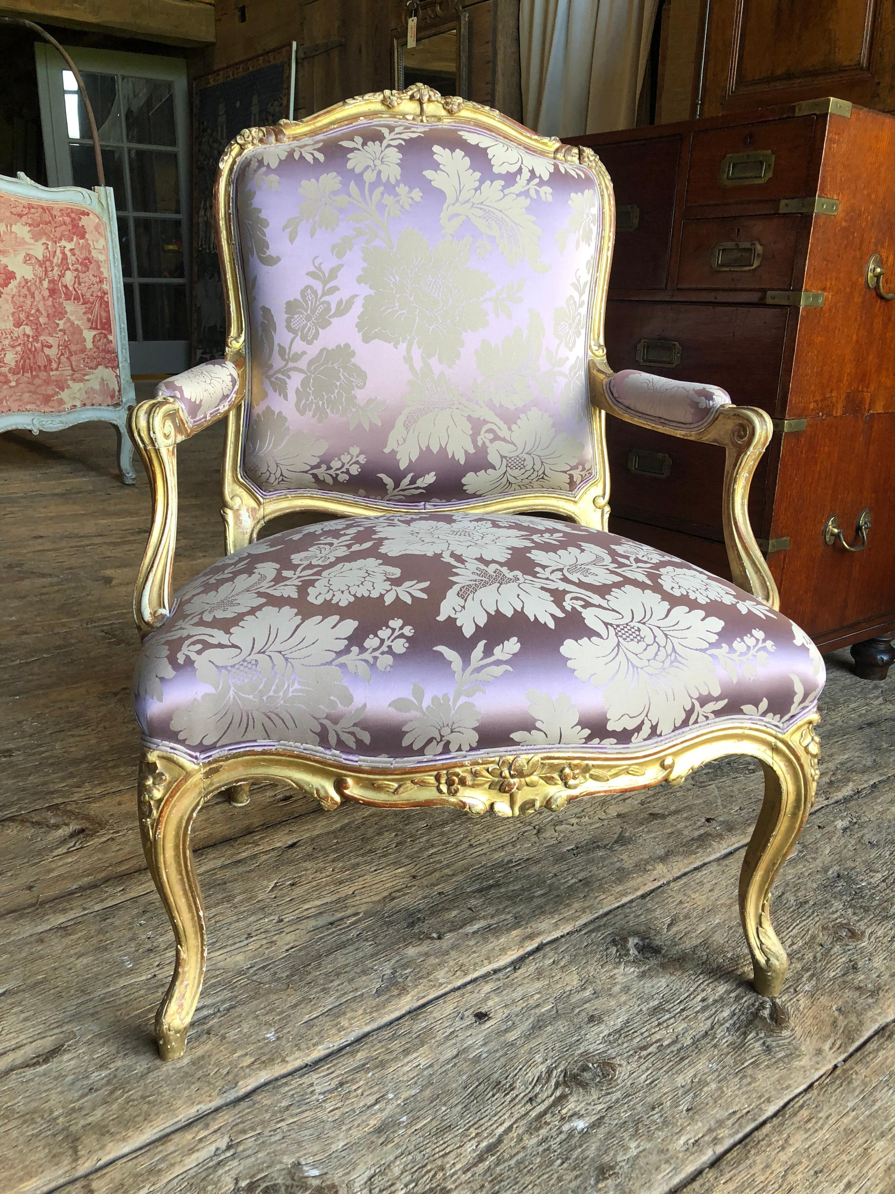 A fine Louis XV giltwood fauteil de la Reine, France, circa 1870, recently upholstered in lavender silk damask fabric, the frame nicely carved with flowers and garlands and water-gilded over gesso and bole.
The gilding is subtly worn in appropriate