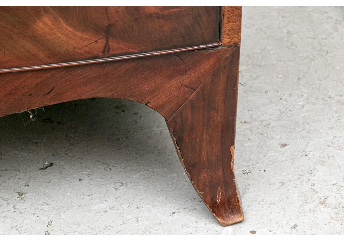 Une grande commode ancienne en acajou avec un dessus à bandeau et deux tiroirs courts sur trois longs, tous avec des moulures sculptées et de fines balles néoclassiques en laiton représentant des temples ronds avec des statues de guerriers. Trous de