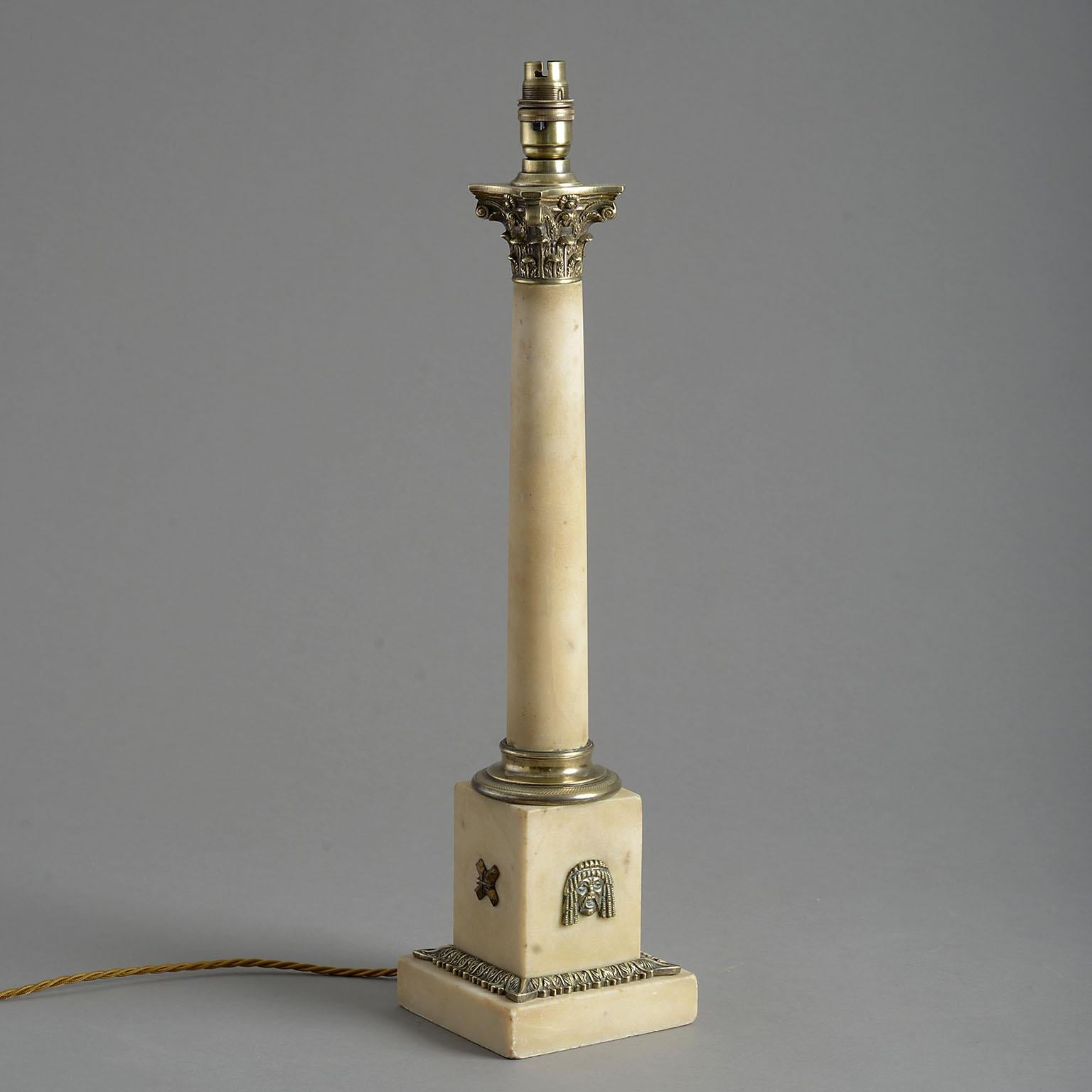 A late 19th century tapering marble column with well detailed brass corinthian capital and waisted socle standing on a square plinth mounted with masks of Tragedy, leaf cast borders and a conforming marble base. Originally an oil lamp and now wired