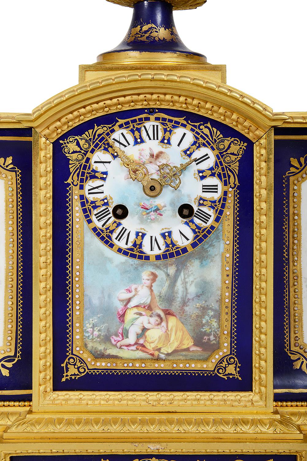 
A fine quality late 19th Century French Sevres style mantel clock, having a wonderful gilded ormolu case with an urn to the top with cobalt blue ground porcelain and an inset classical hand painted scene of a reclining cherub, lion mask handles to