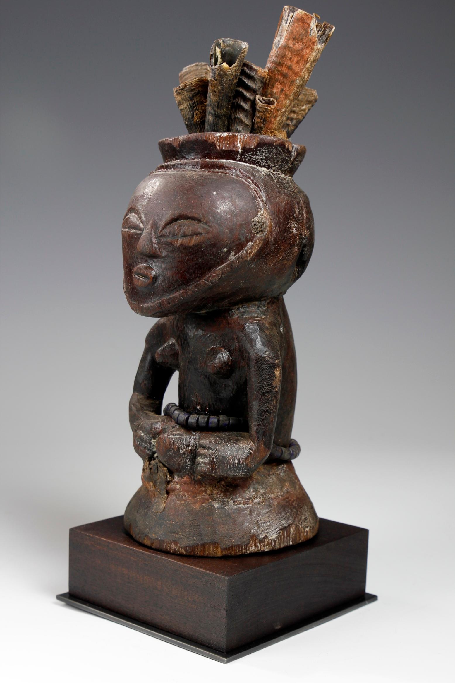 Diese schöne Fetischfigur aus der Luba/Kusu-Kultur in der Demokratischen Republik Kongo stammt aus dem frühen zwanzigsten Jahrhundert oder früher, aus dem neunzehnten Jahrhundert. Die geschnitzte Figur hat einen ausgeprägten Kopf,  mit einem Paar