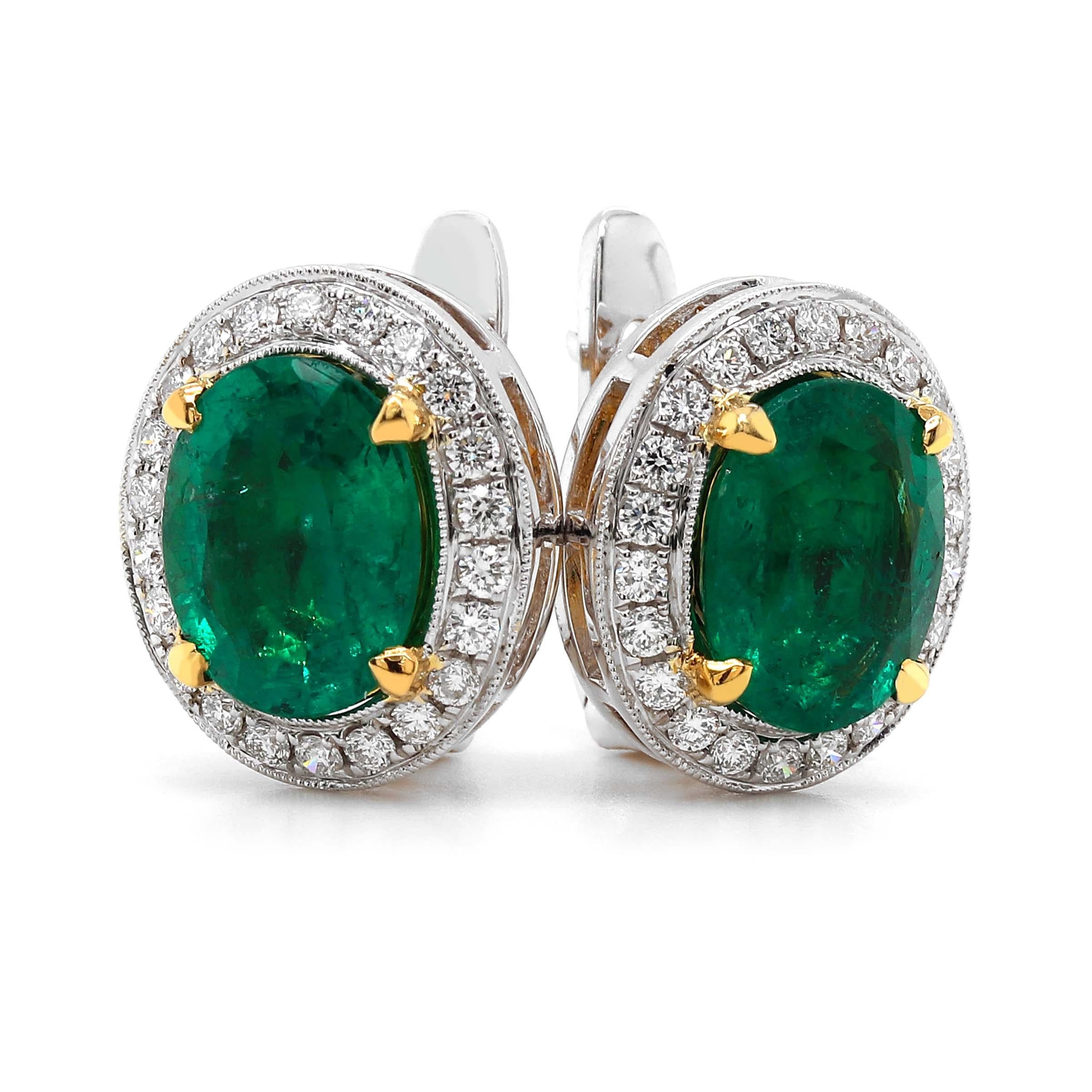Two Fine 2.50 carat oval emeralds of about 2.50 carats. The emeralds are surrounded by 44 round brilliant cut diamonds of about 0.67 carats with a clarity of VS and color G. All stones are set in 18k 2 tone gold. The total weight of the earrings is
