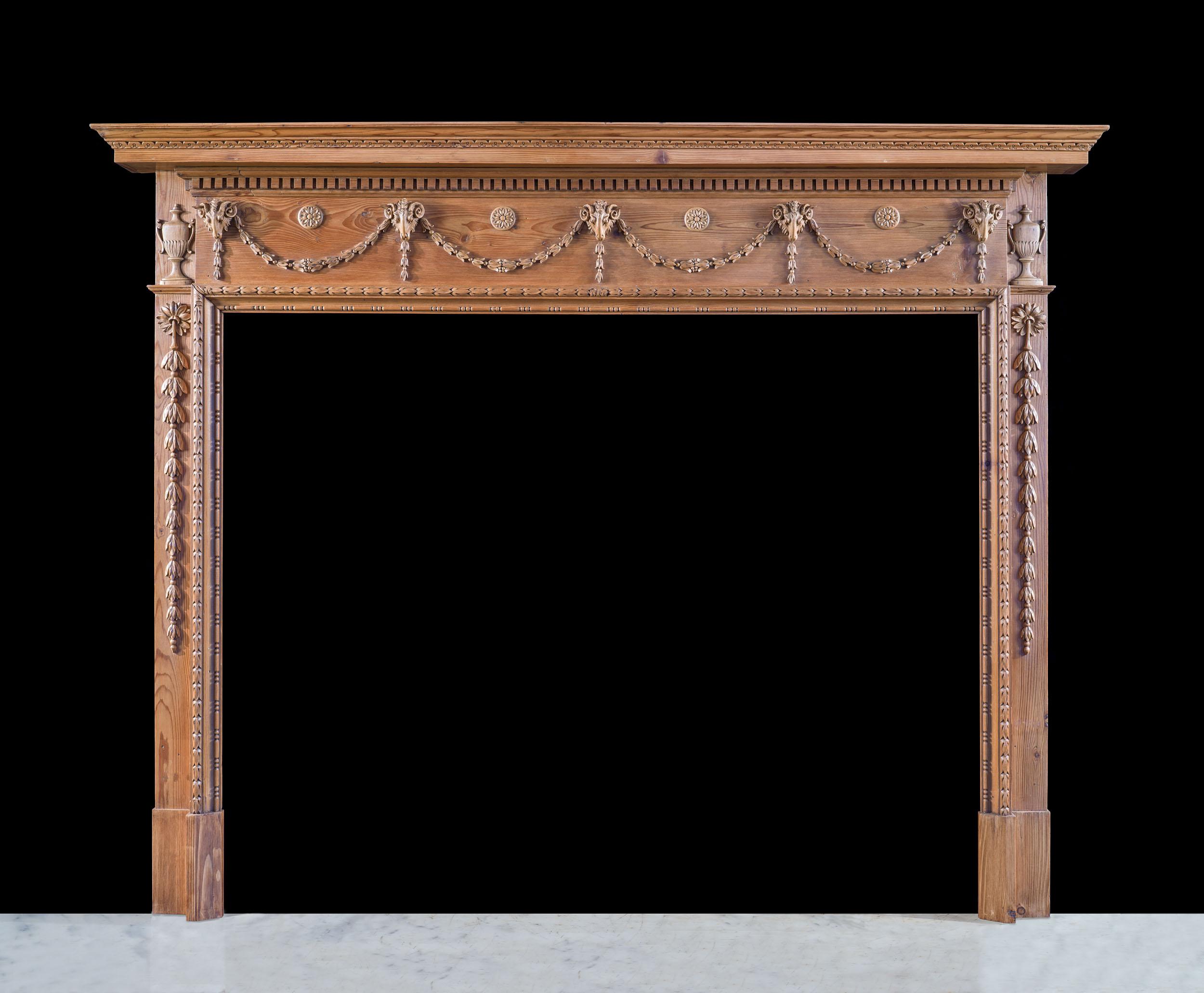 Très belle cheminée en pin de style Adams, datant de la période édouardienne. L'étagère, avec sa tablette inférieure à denticules, est montée sur la frise magnifiquement sculptée, constellée de têtes de bélier suspendues à des guirlandes de