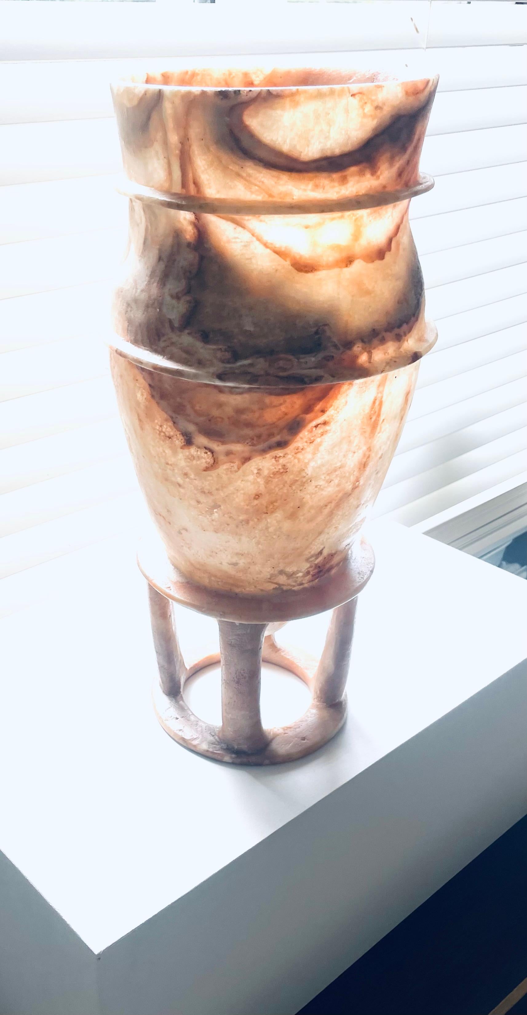 Bien  urne en albâtre inspirée de l'Égypte ancienne.
L'urne repose sur quatre pieds cylindriques.
Probablement en Italie à la fin du 20ème siècle.