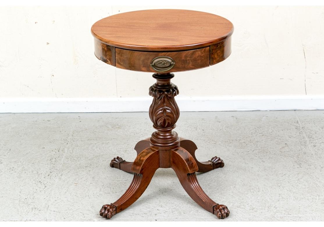 Table centrale de petite taille, fabriquée en ébénisterie, avec un plateau circulaire. Le plateau est monté sur une frise en bois figuré avec deux tiroirs alternant avec les panneaux de la frise. Les tiroirs présentent de fines balles ovales en
