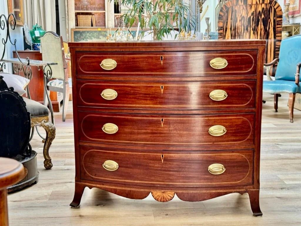 A Baltimore, Maryland Federal Inlaid Bowfront Chest of Drawers, c. 1800.The bowed rectangular top above a case fitted with four string inlaid drawers above an apron having a fan form inlay centering a figured skirt on splayed, bracket feet. Mahogany