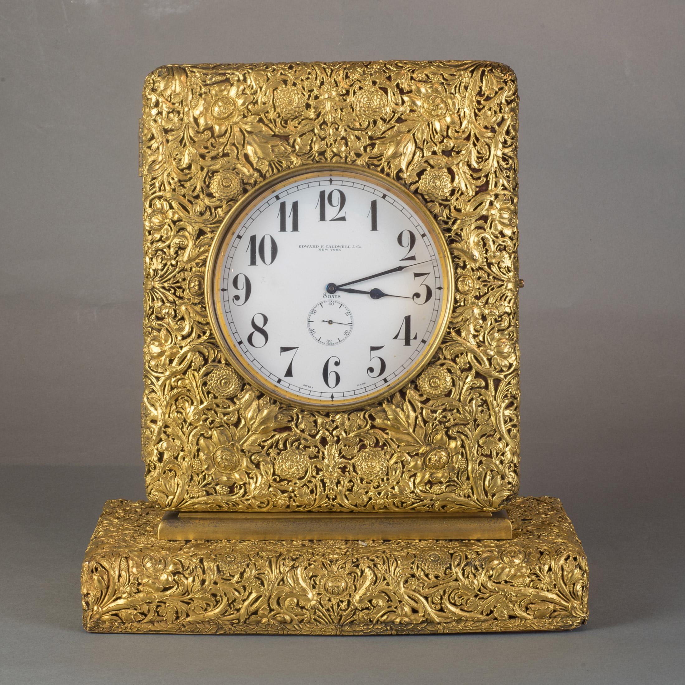 Antique chased Ormolu clock case ornamented with hand pierced all over foliate pattern scrollwork, achieved through repousse and engraving, enclosing a pocket watch-style clock bearing Edward F. Caldwell on the clock face. A silver oversized pocket