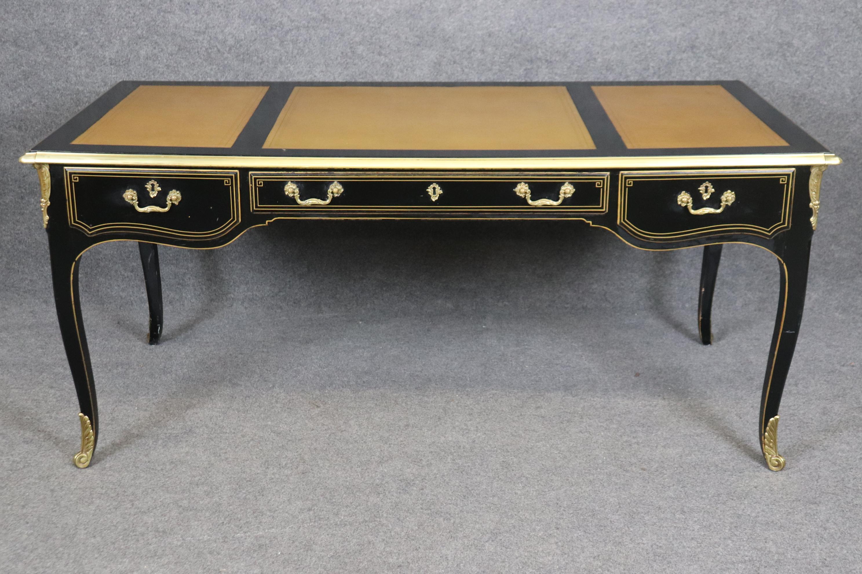 This is a beautiful American-made desk with age -crackled leather and a nice original ebonized frame and gold pinstriping with brass ormolu.   Measures 67 wide x 30 tall x 33.25 deep. Dates to the 1970s-80s era. 