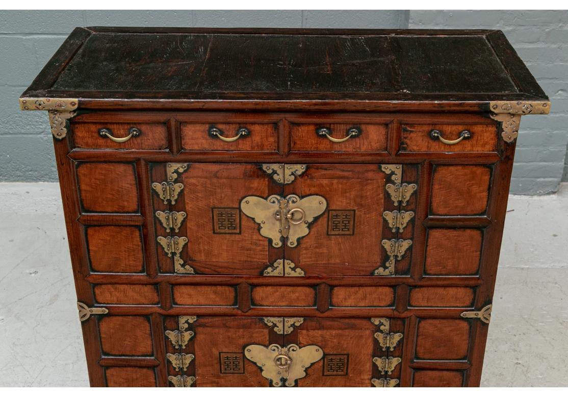 An intricately decorated Korean Chest with fine wood graining and fine presentation. Each door with an inscribed panel in calligraphy. With two-part recessed side panels and raised on incurved feet linked with flat side stretchers. 
W. 35 1/4