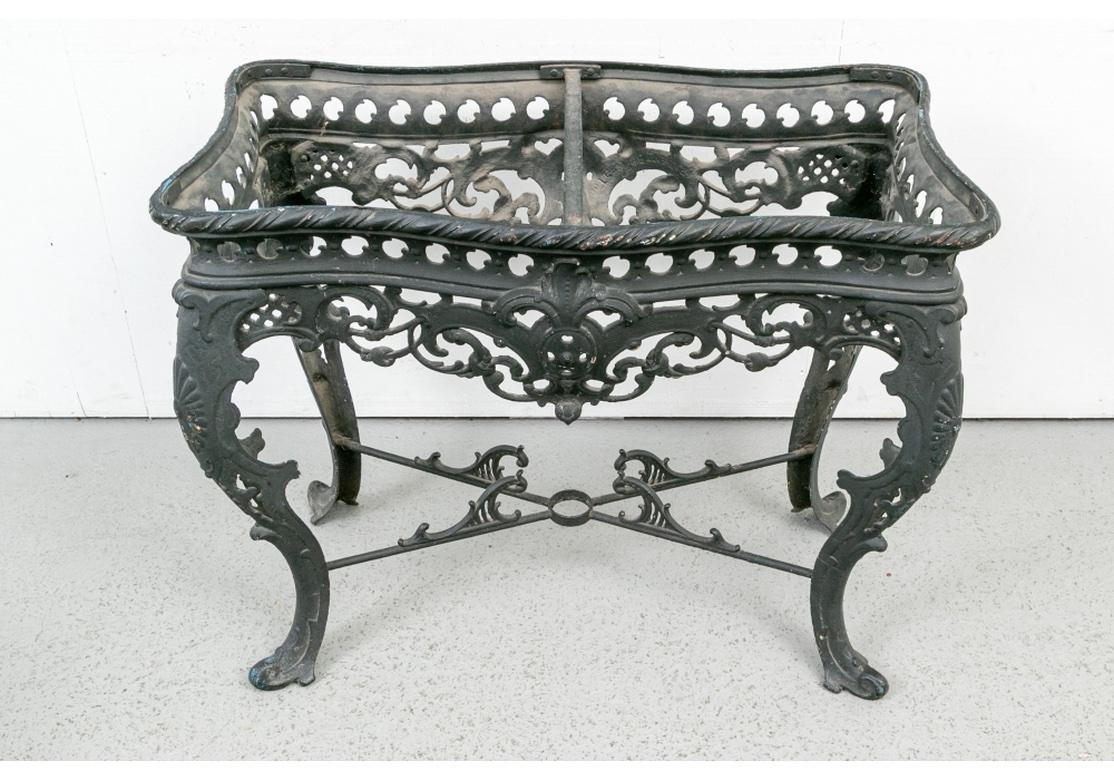 A shaped iron table in black paint with elaborate openwork scrolled frame with palmette motifs. The wide cabriole legs with X stretcher decorated with raised foliate scrolls and center circular opening. With a particularly fine conforming brown,