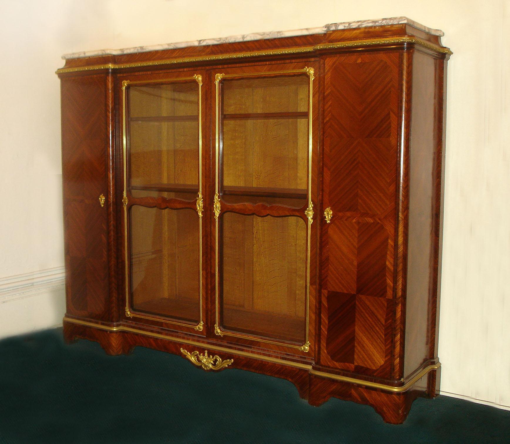 A Fine and Grand Late 19th Century Transitional Style Gilt Bronze Mounted Vitrine/Bookcase By Paul Sormani

Paul Sormani

A long marble top above a bronze frieze with two glass center doors and two side quarter veneered parquetry doors.

The inside