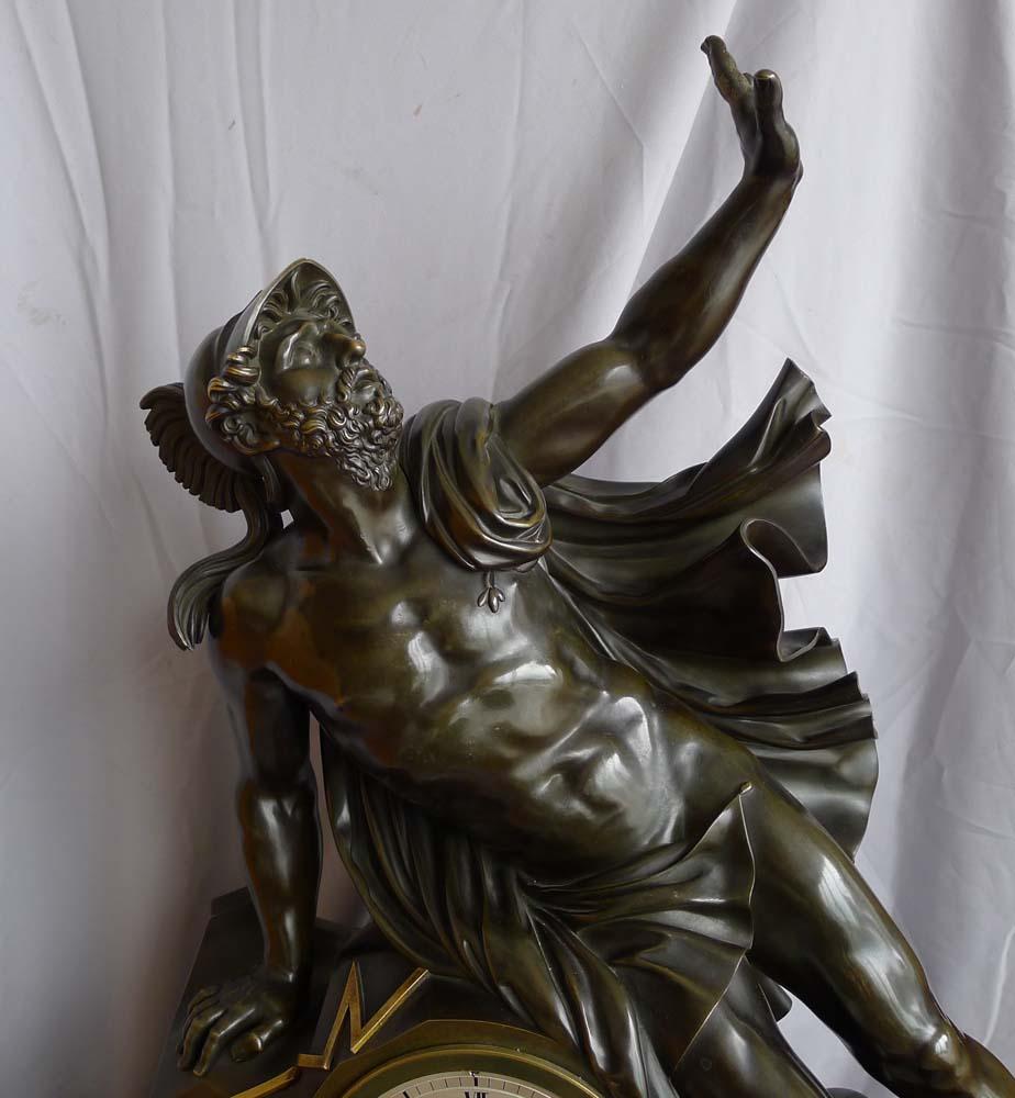 Fine and large antique Charles X mantel clock of Ajax. The clock features the magnificent figure of the Trojan warrior Ajax leaning upon the clock case. He is wearing a cloak and his war helmet. The clock has been made of well patinated bronze and