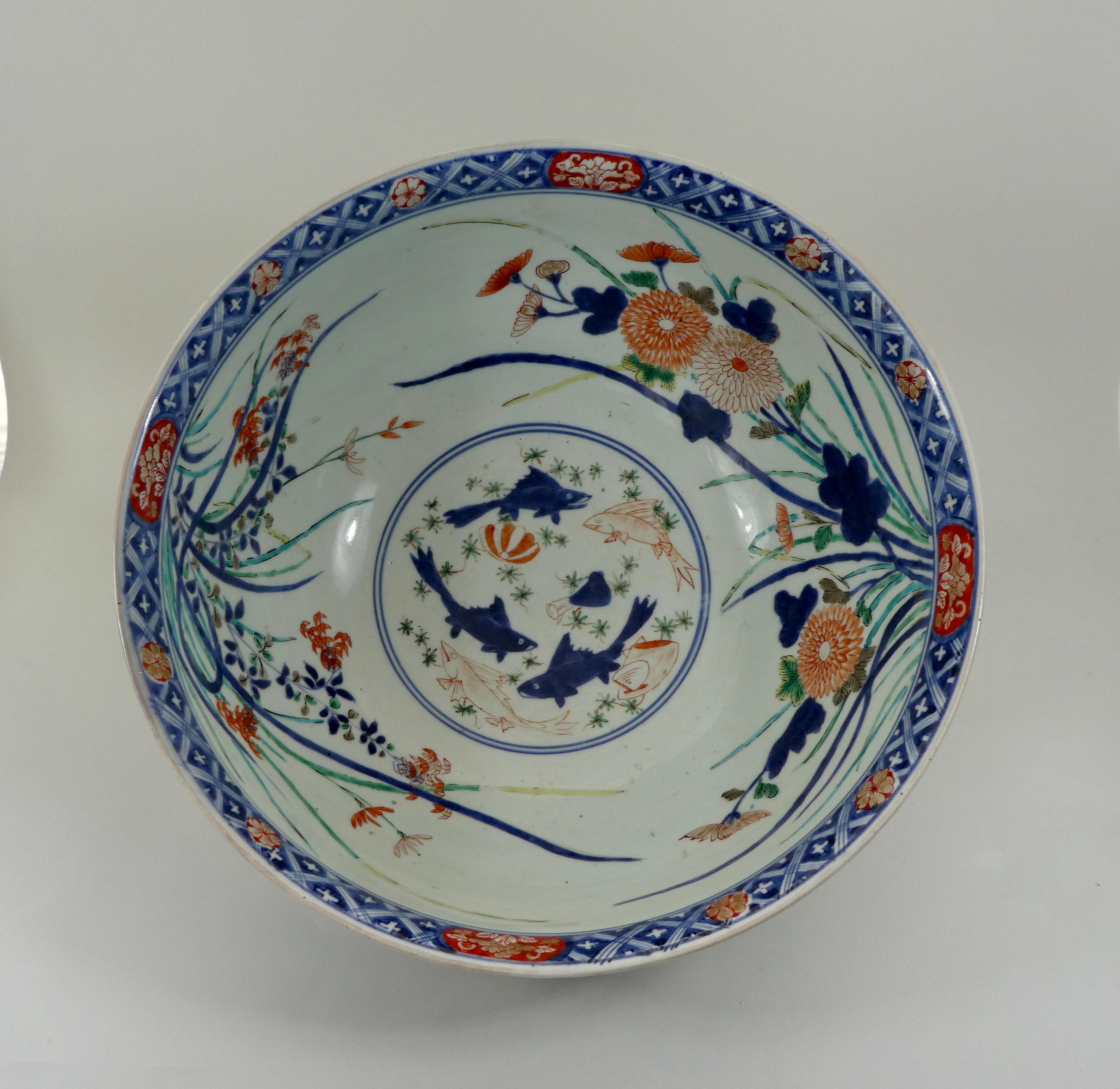 A fine and large Japanese Imari bowl, late 17th century, Genroku, period (1688-1704).
Decorated in iron-red, yellow, green, light blue, aubergine and black enamels, and gilt on underglaze blue, the interior with a central roundel containing fish