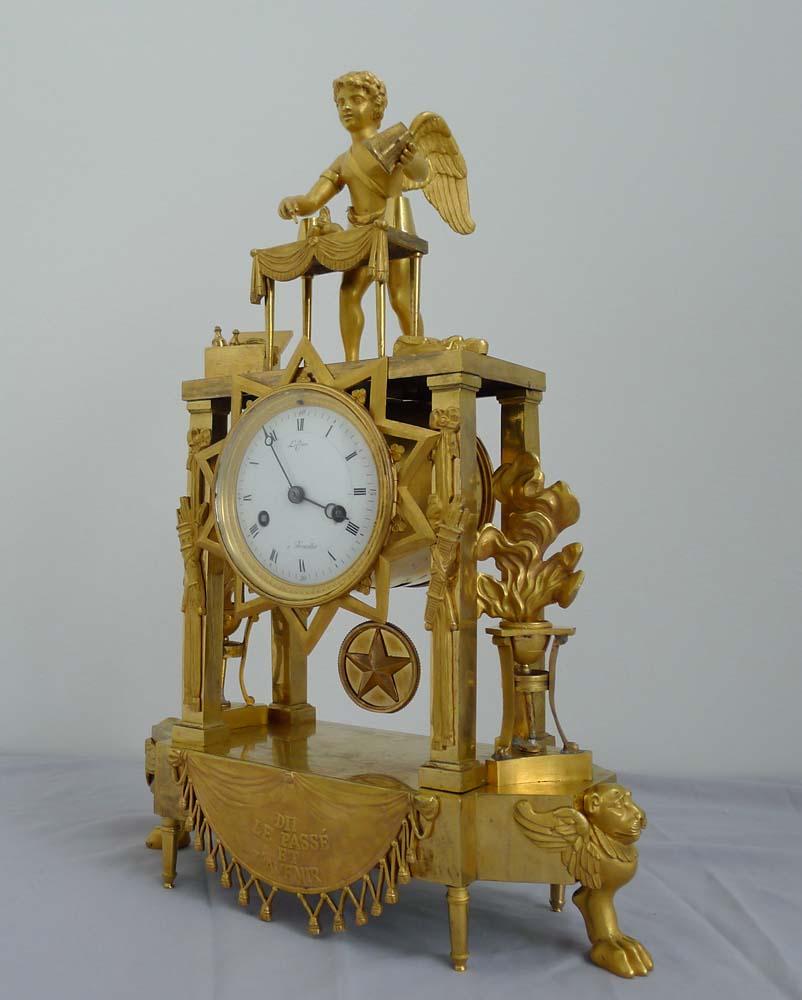 Fine and rare French Empire ormolu clock of Cupid as magician, uncovering flaming hearts with the 3 cup trick. The shaped base with four tall ormolu feet to front and back but with winged lion paw feet to each side. To the front of the base a