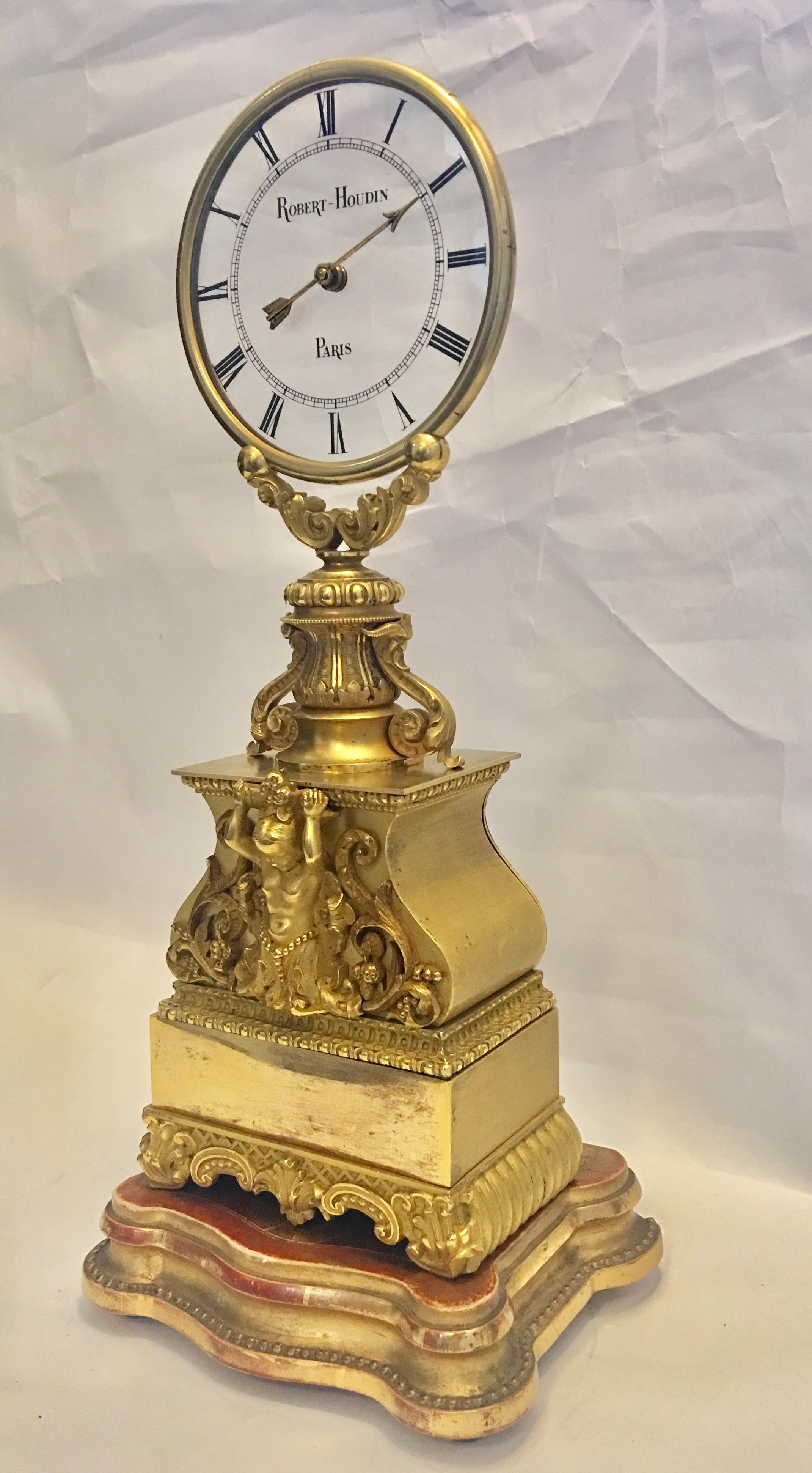 A fine and rare patinated and gilt bronze mystery clock by Jean Eugene Robert-Houdin, Paris, mid-19th century. The transparent glass dial within a gilt bezel above the vase shaped patinated case, enhanced with an applied gilt putto supporting a pair