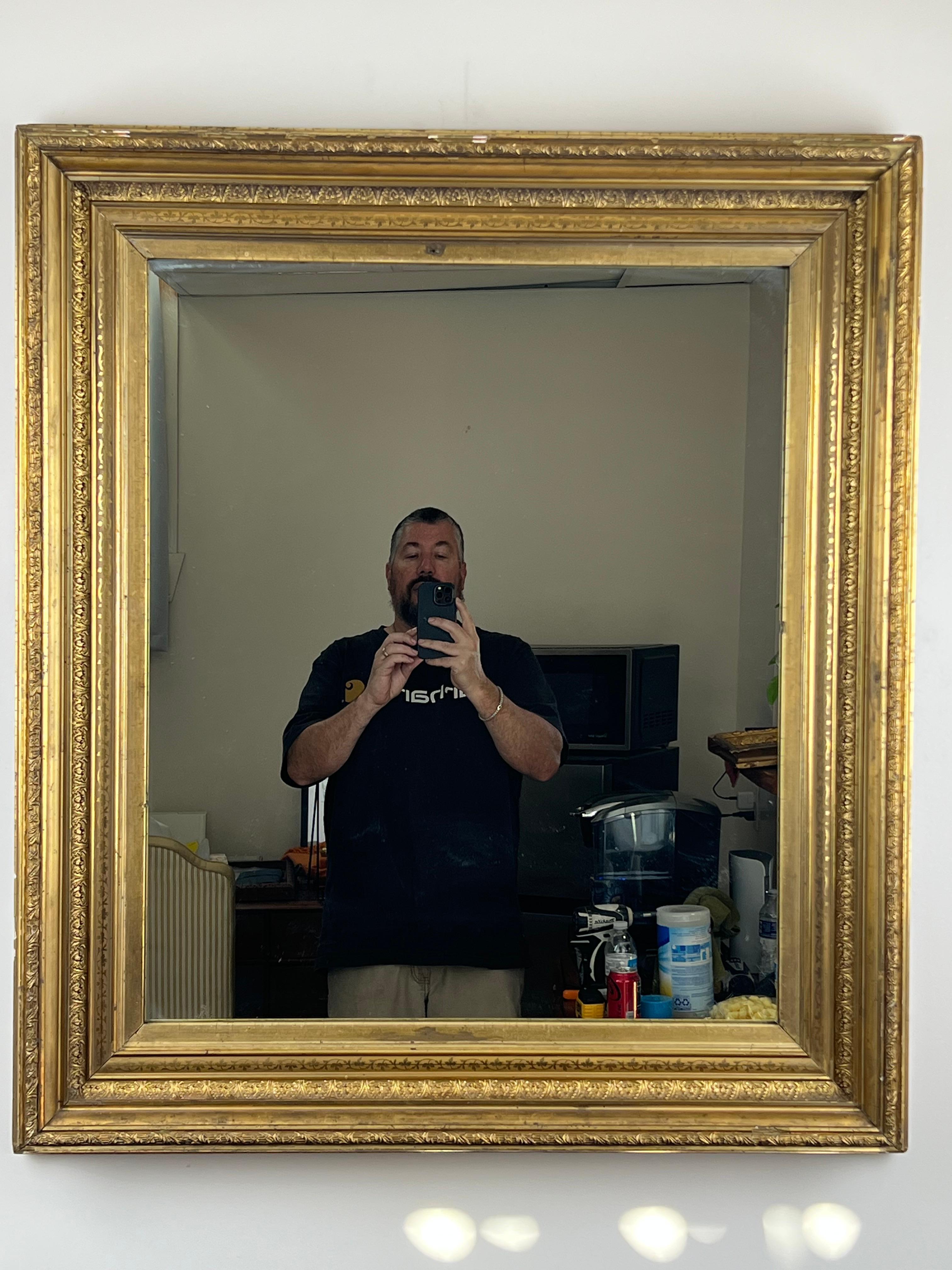 Ce beau miroir ancien en bois doré du XIXe siècle présente un profil élégant et intemporel, réalisé avec la sculpture richement détaillée qui définit les travaux décoratifs les plus raffinés de l'époque. Le cadre présente de profondes moulures en