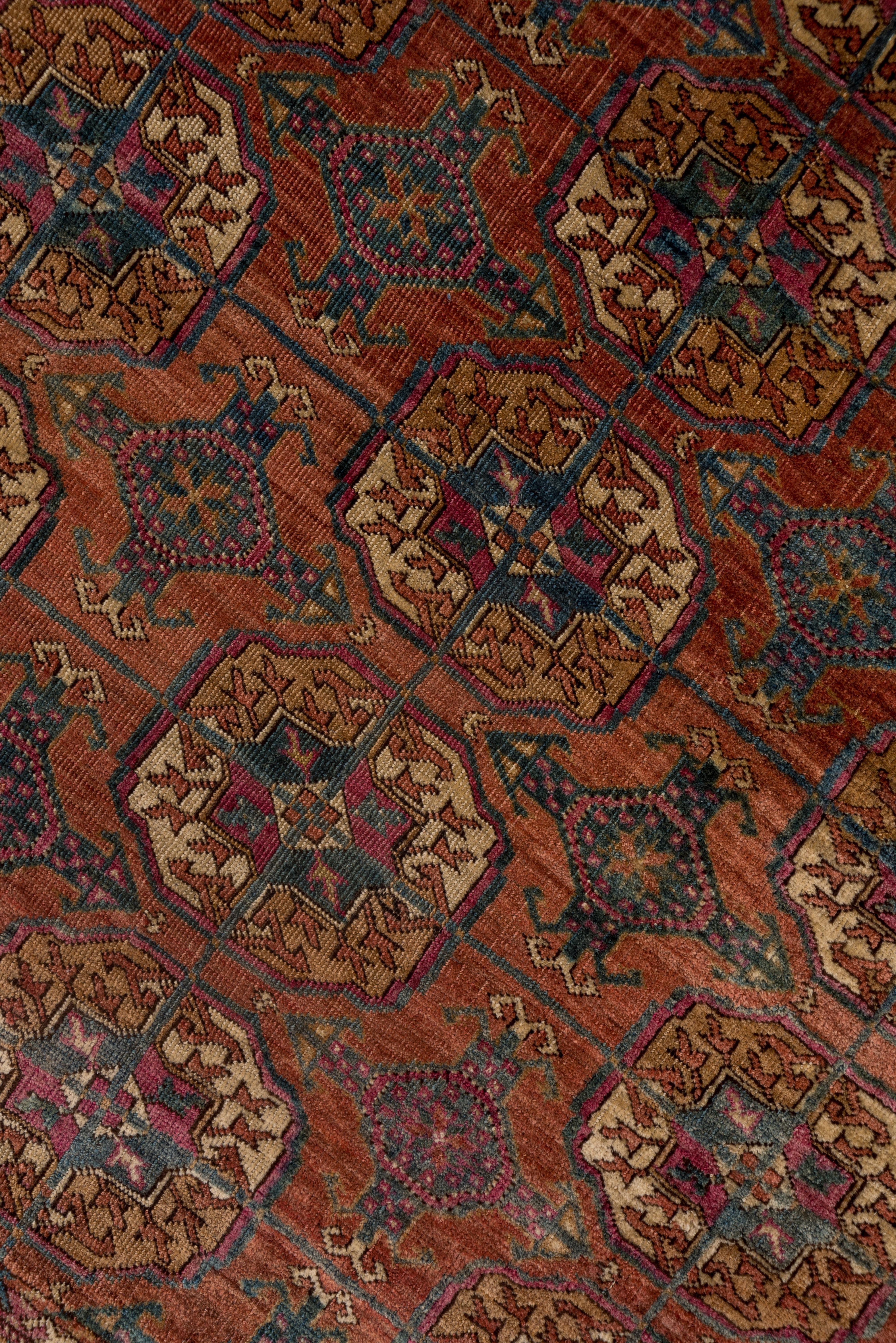 The abrashed rusty red field of this nomadic central Asian carpet displays five columns of characteristic quartered guls joined in a square lattice with kurbagh minor guls between. Main red border of rayed octagons enclosing crosses. All wool