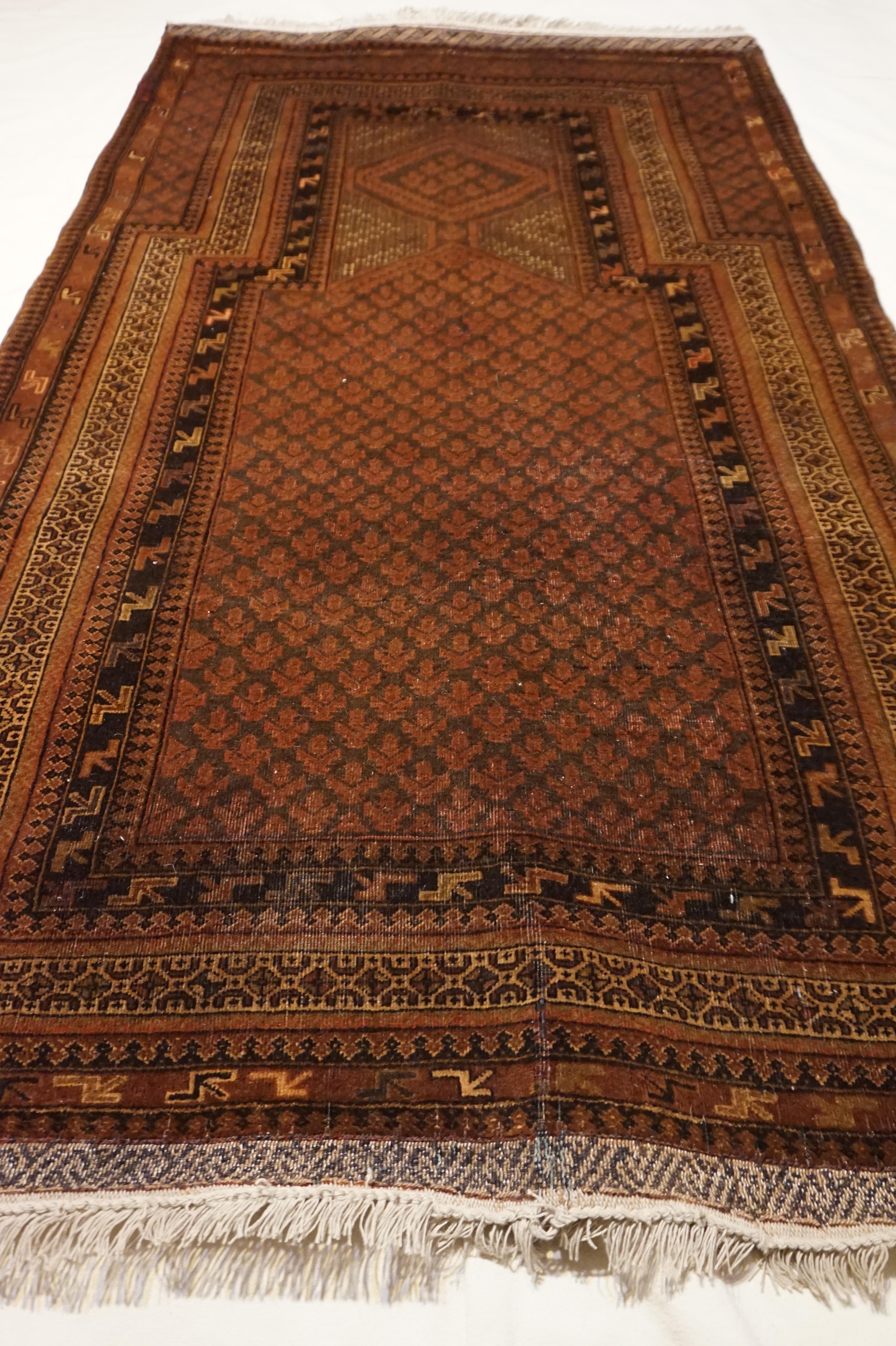 Subtle and rich earthy tones dictate this masterfully hand knotted Afghan prayer rug. The primary image is more indicative of the natural appearance of this rug. Meticulous details adorn all the way down to the fringe which is woven like a