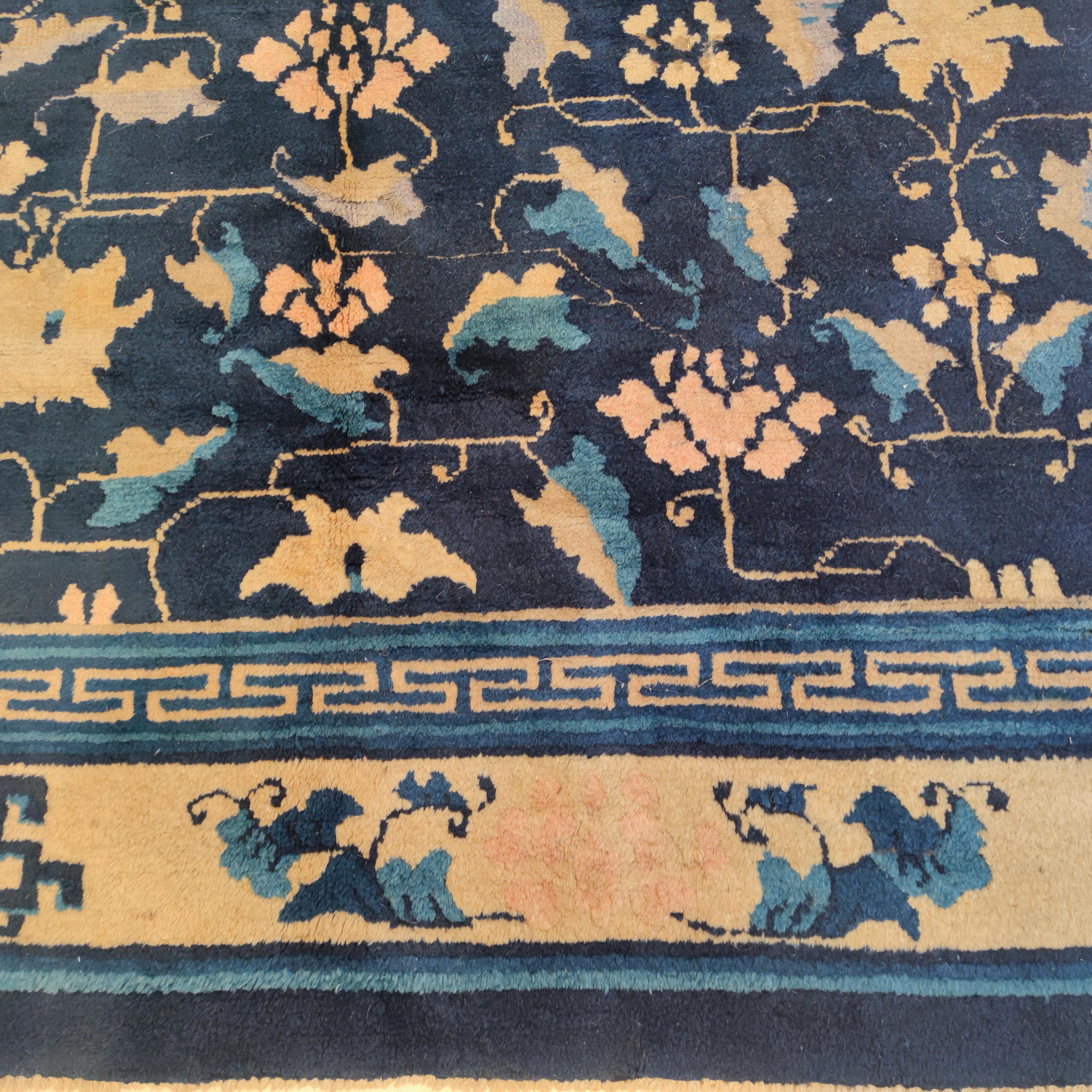 A very finely woven antique Chinese rug woven in the Imperial workshops of Peking. Distinguished by an elegant pattern of scrolling lotus flowers on an indigo background, this type represents the highest quality of weaving originating from China