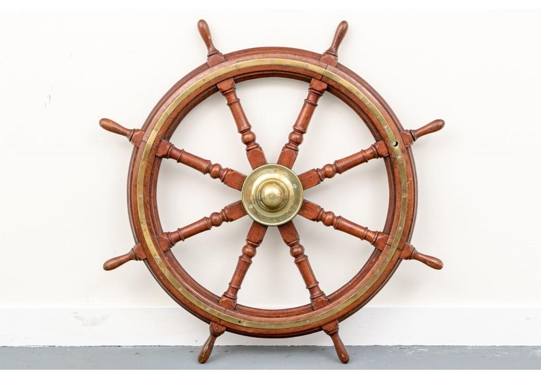 An antique solid mahogany Ship’s Wheel with good size and weight. The axle has an iron core and polished brass front cap and both sides of the wheel have handsome brass inlay. 
Condition: The overall condition is very good with only expected and