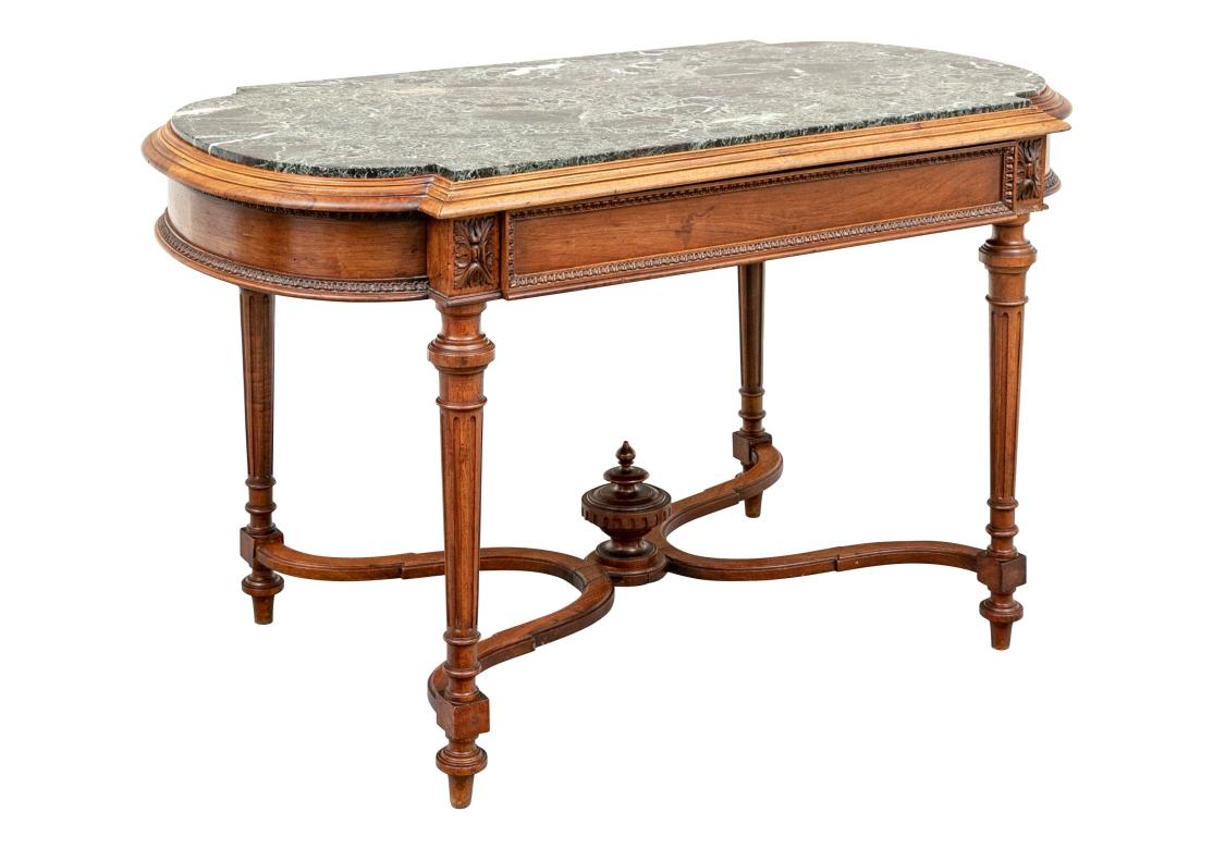 A finely crafted walnut shaped table with curved ends and carved edge with an inset green marble top. The apron with a carved leafy band and a single drawer. Leafy panels are on top of the tapering fluted cylindrical legs. With a fine carved