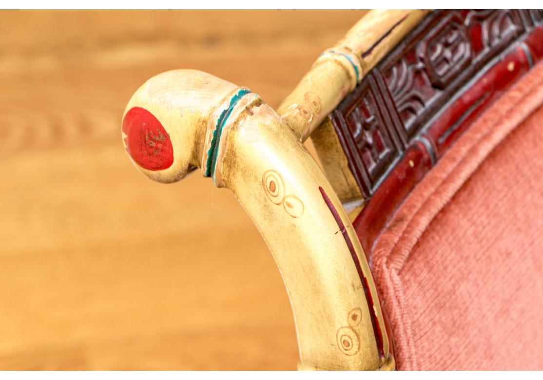 Una deliziosa e coloratissima poltroncina in stile Chippendale con struttura in legno di bambù finto, schienale incastonato con struttura in bambù finto dipinta di rosso e seduta e schienale in tessuto color rosa. Il dipinto è sorprendente con una