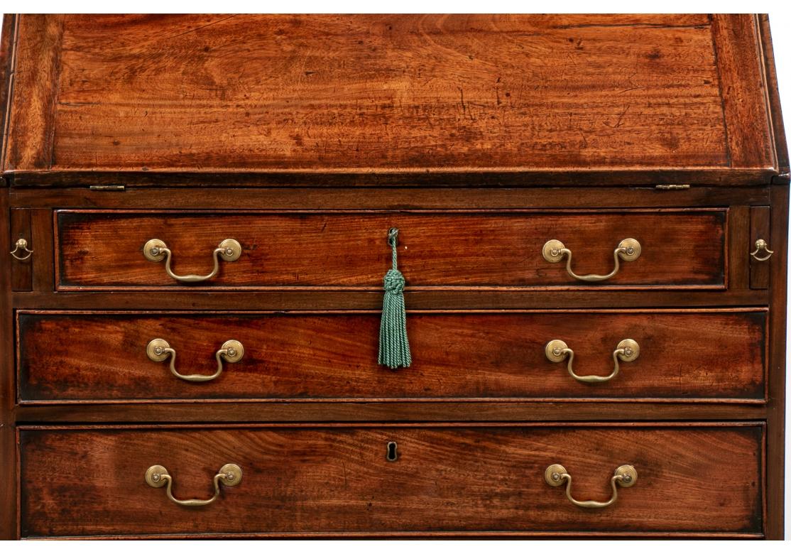 With four graduated drawers with fine brass pulls. The slant front opens to a fitted dark mahogany interior with drawers, cubby holes and a center compartment with door. The two half columns decorate two pull out compartments. Raised on all bracket