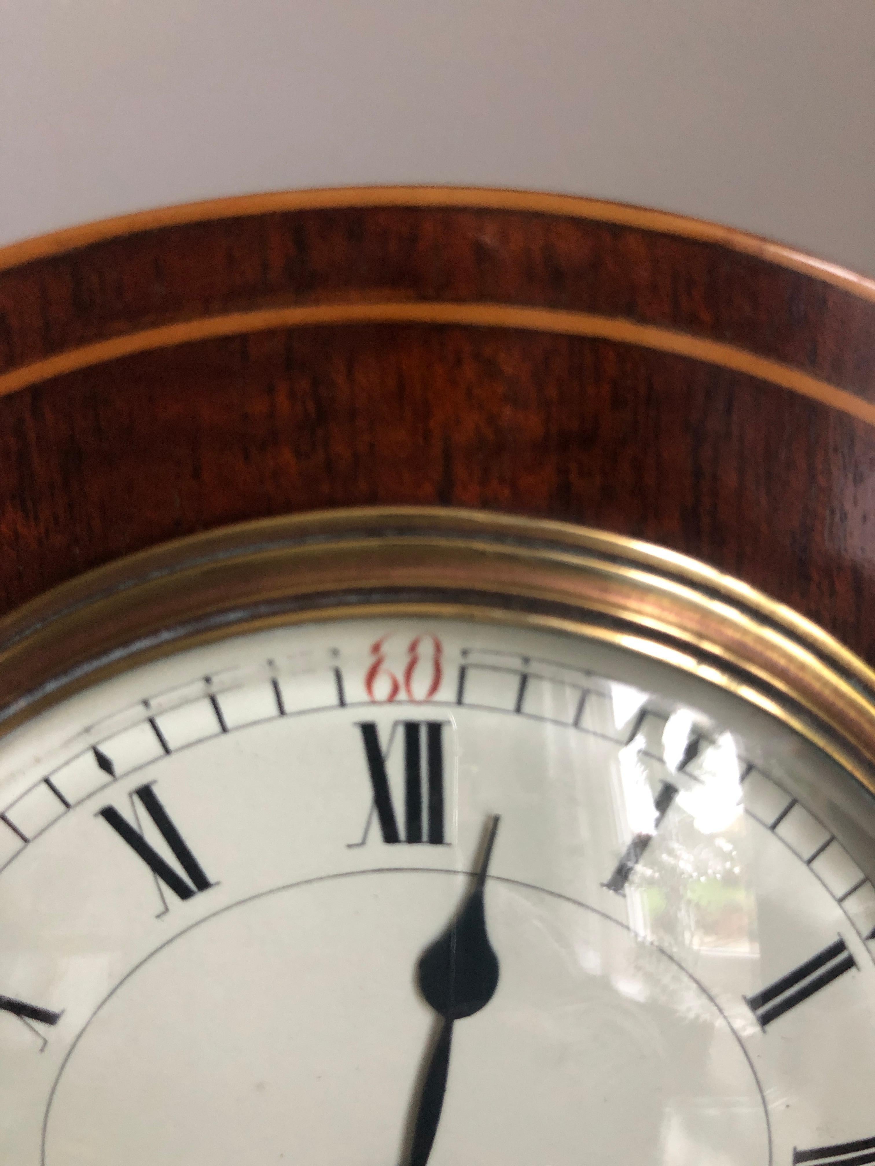 Belle horloge de bureau édouardienne en acajou marqueté, avec un magnifique boîtier en marqueterie en forme de ballon et des pieds à boule en laiton d'origine. Un élégant cadran émaillé avec des aiguilles originales avec un mouvement de 8 jours. Il