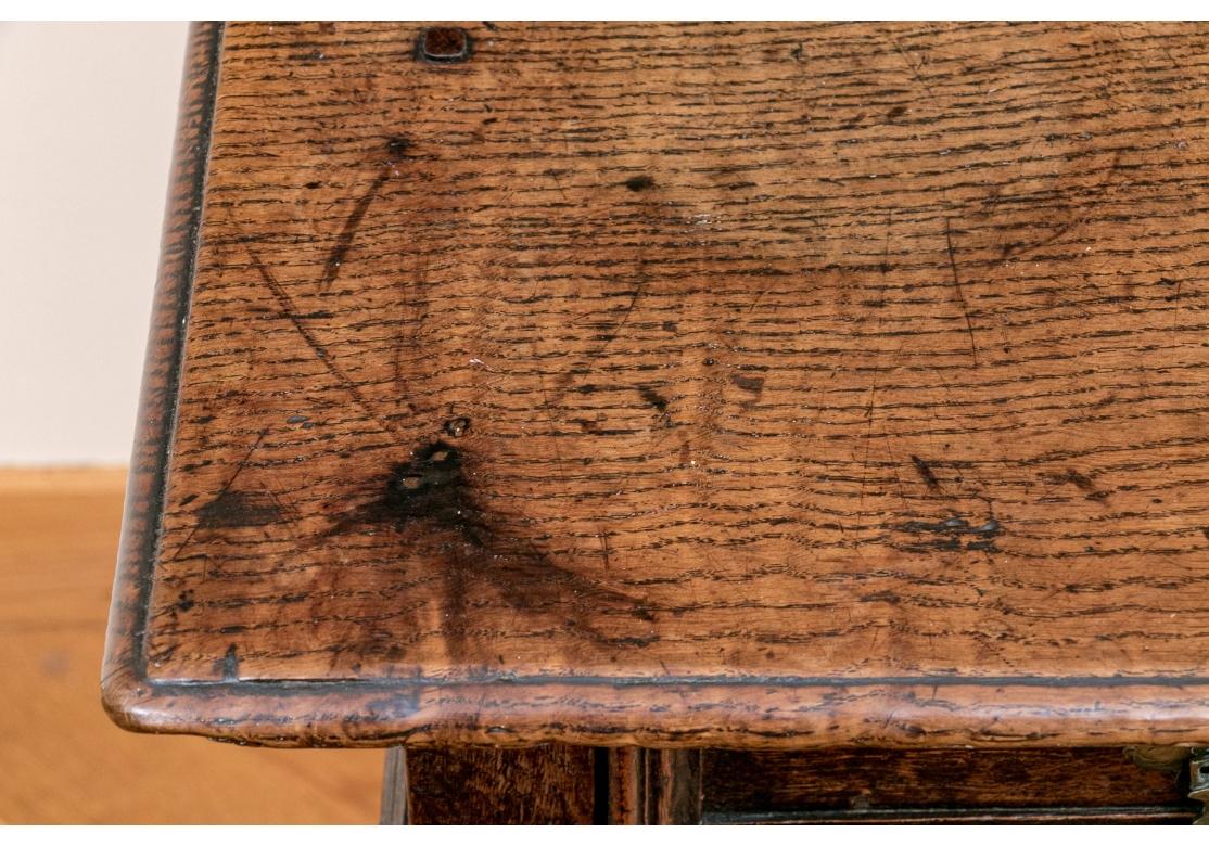 Une très belle table à écrire anglaise ancienne avec une forme traditionnelle, une construction à chevilles et un beau grainage. Plateau rectangulaire surmontant deux tiroirs courts, supports tournés et base à brancard.  

Dimensions : 28 1/2