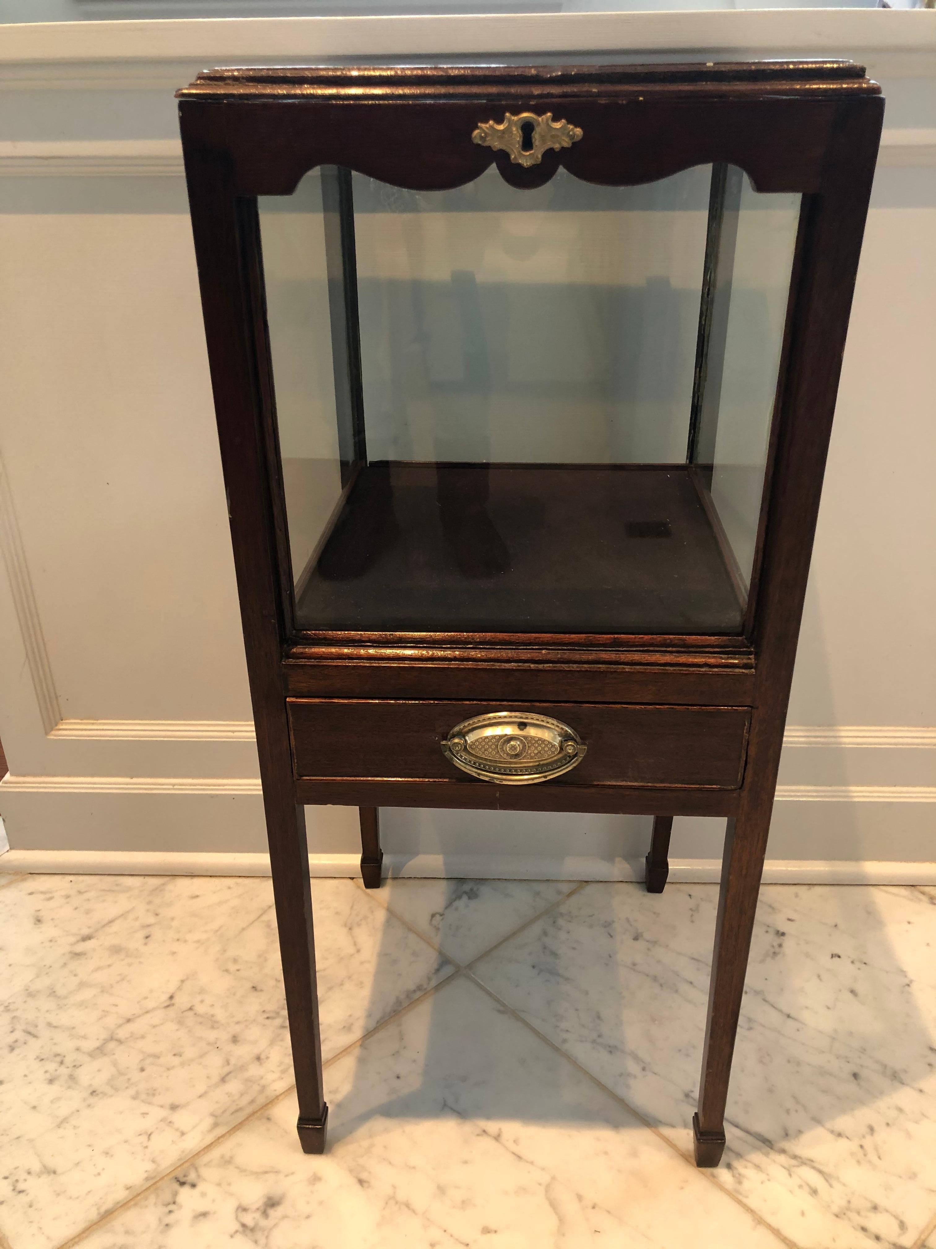 An antique oak vitrine from England cleverly designed to showcase a collection having glass sides and top with scalloped edge wood surround around the top. The top lifts up and there is a single drawer. The escutcheon and handle are brass (no key).