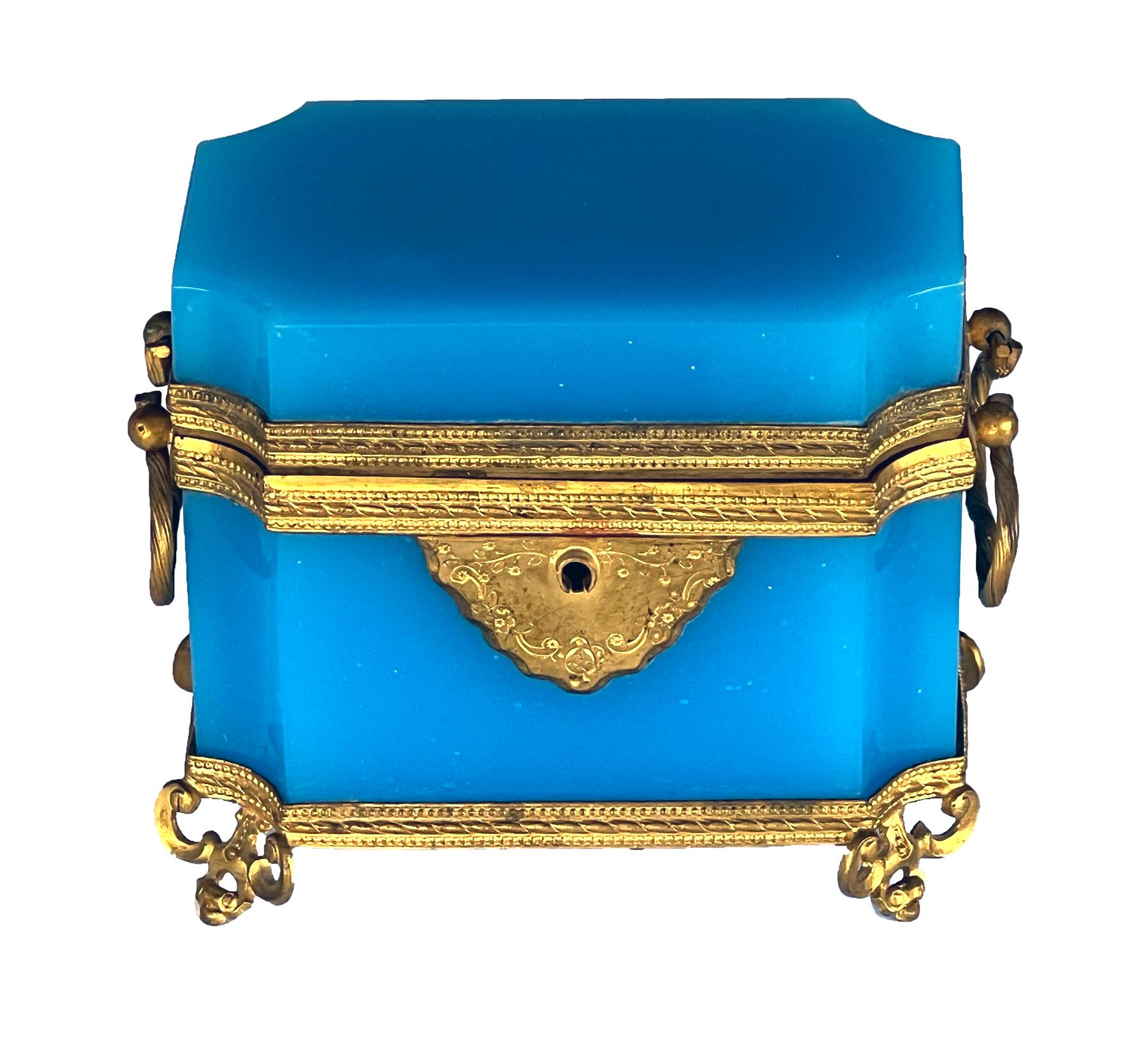 the rectangular box with curved beveled corners, loop handles and fine dore bronze mounts; raised on intricate openwork dore bronze feet; the hinged lid opens to reveal two crystal perfume bottles with miniature eglomise paintings of Paris