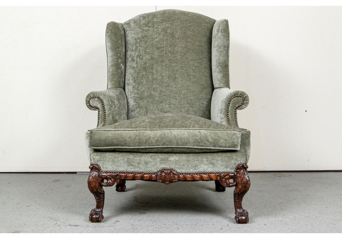 A very fine Wing chair with very good comfort and solid sit. Boldly carved frame with gadrooned edges and center triple feather motif on the front. The wood with fine grain and finish having foliate scrolls and curved heavily carved leafy legs with
