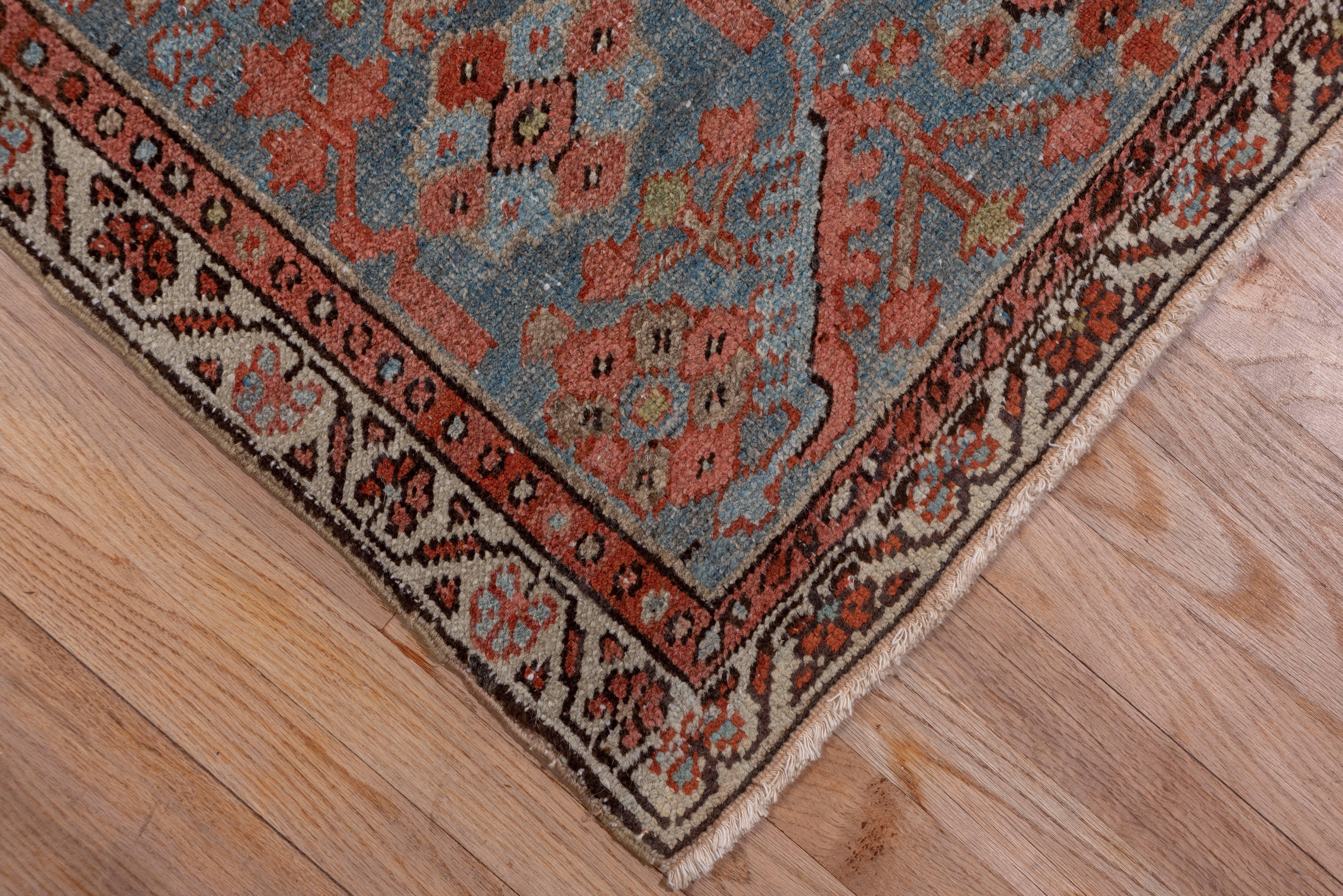 This rural NW Persian carpet presents a green octogram medallion with tonally matching ragged palmette pendants on the mellow madder ground. The light blue corners and border details, along with the natural dye palette overall give this carpet a