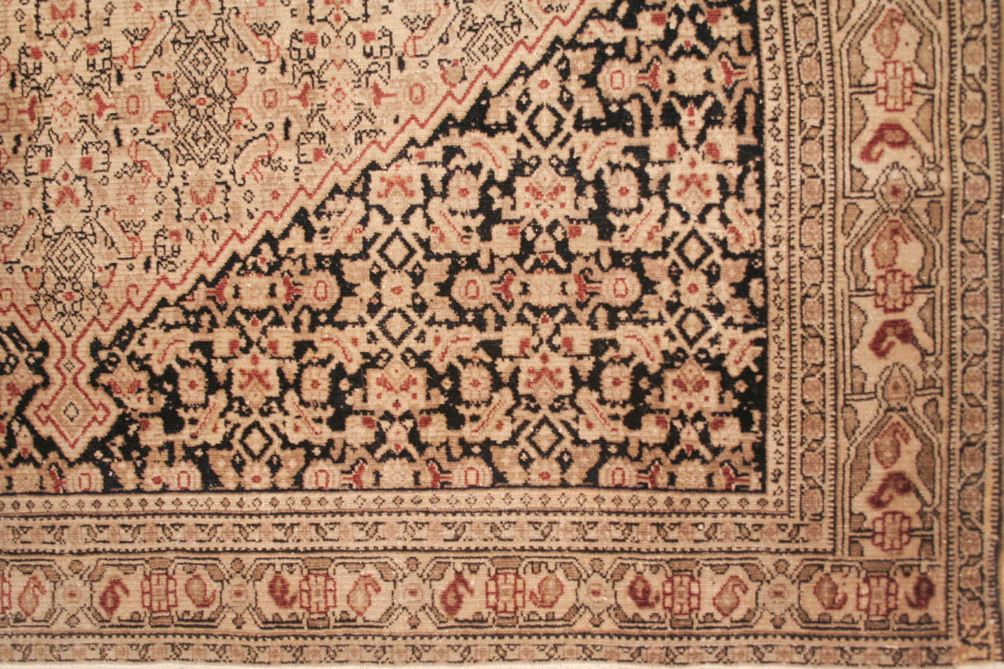 Un tapis Senneh antique très finement noué, caractérisé par un médaillon en forme de diamant placé dans un cartouche ivoire sur un fond bleu indigo. La composition est entièrement remplie par le motif dit herati, qui consiste en une unité répétitive