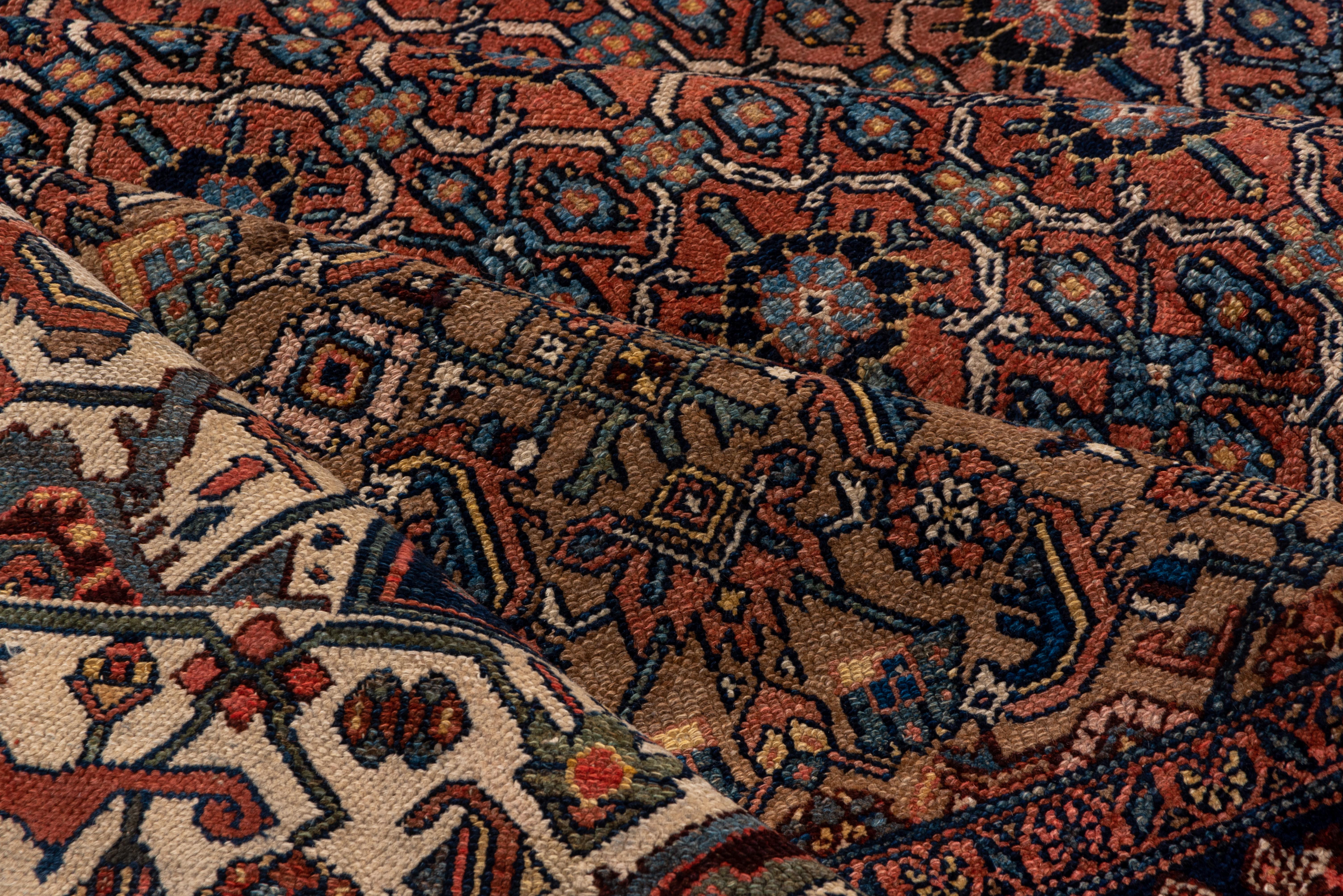 From a famous village in the Greater Hamadan Weaving Area, this large carpet shows a curvy oval ivory lattice on a camel-tone ground, with a large, tall jagged tall oval medallion enclosing a broken Herati design. En suite corners. Ecru main border